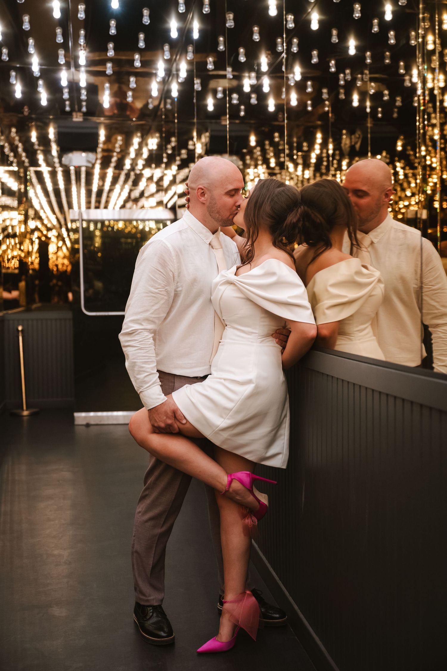 Intimate dance moment captured under warm string lights in an indoor venue.