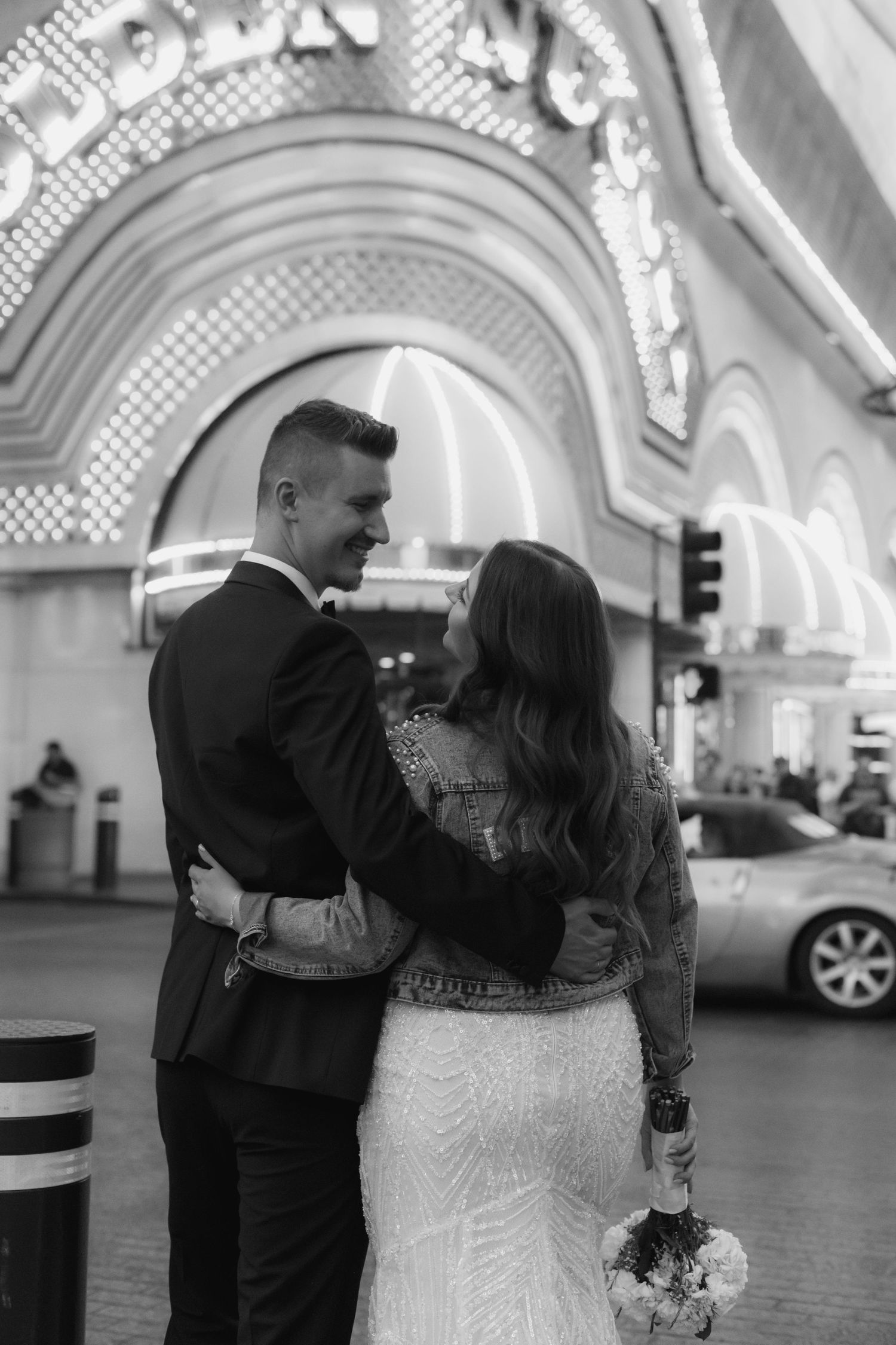 Black and white photo of couple under illuminated casino archway.