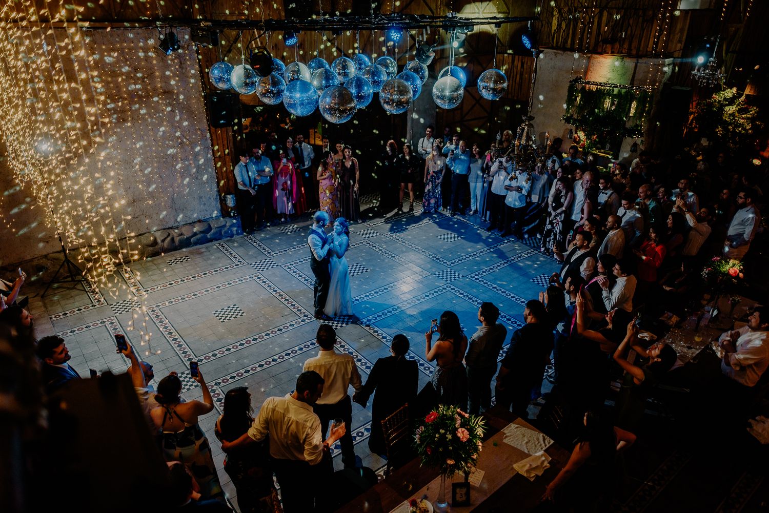 A spectacular first dance moment surrounded by guests under blue lighting and sparklers.