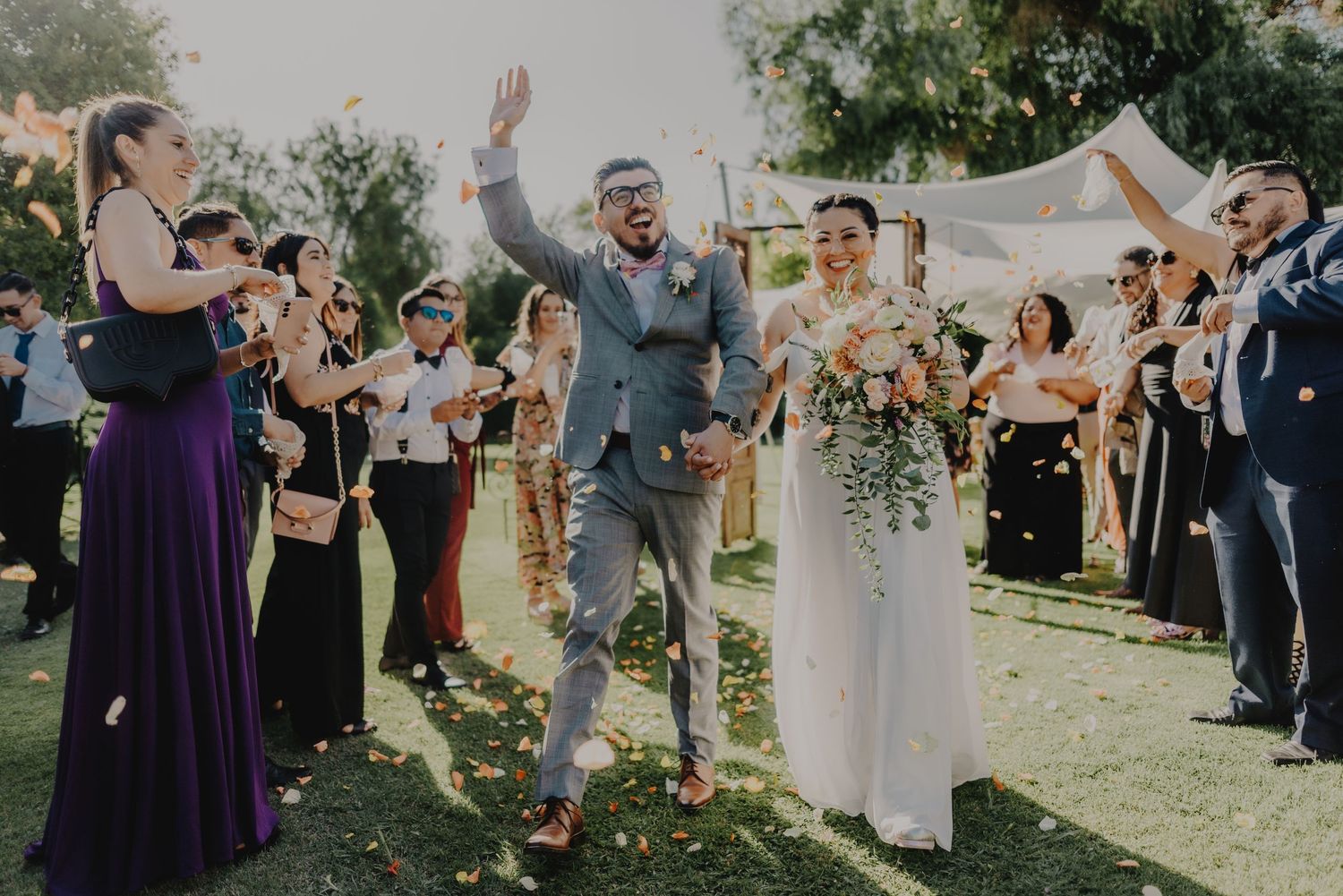 Wedding celebration with joyful guests cheering outdoors in natural lighting.