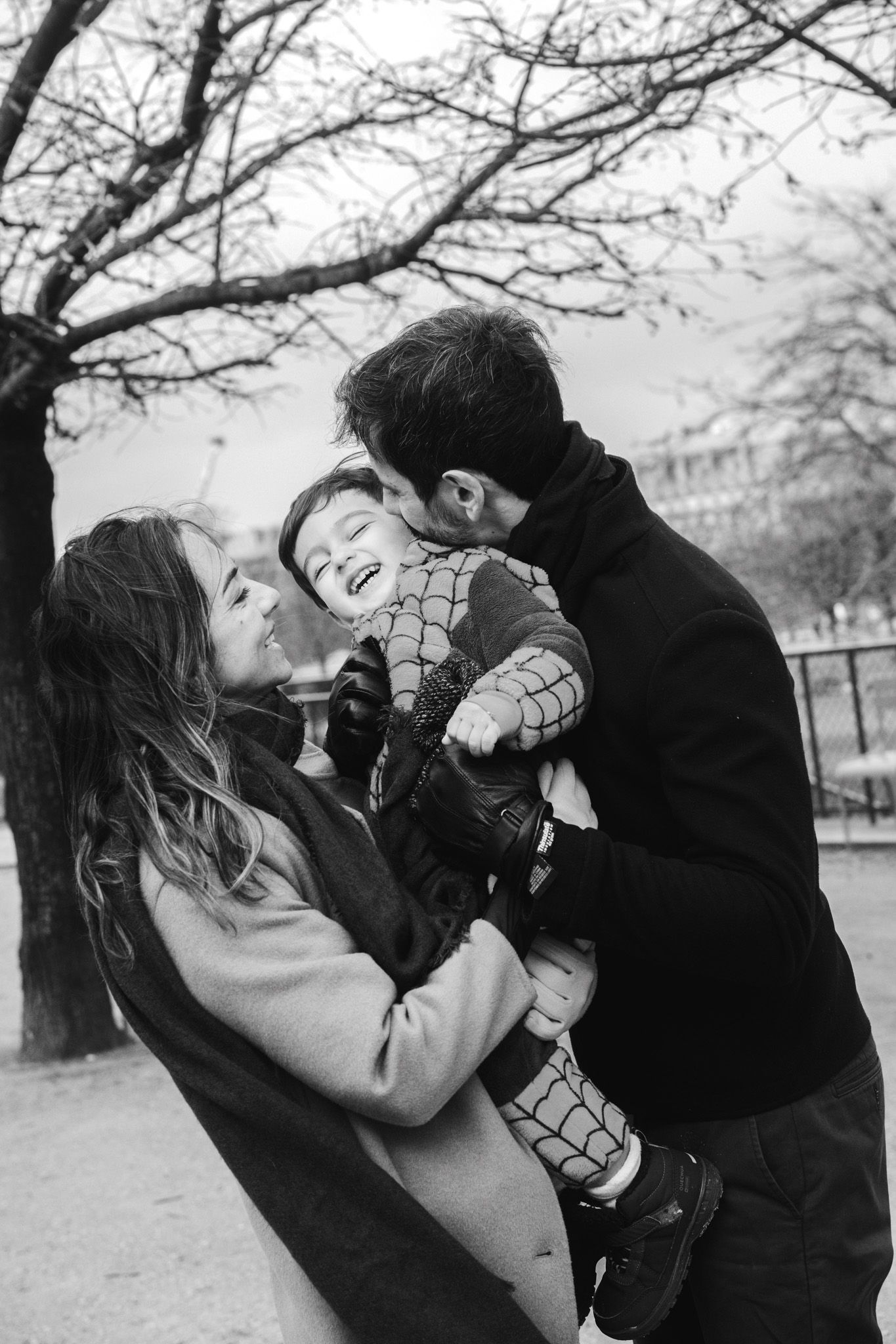 A joyful family moment captured in black and white as they share laughter together outdoors on a winter day.