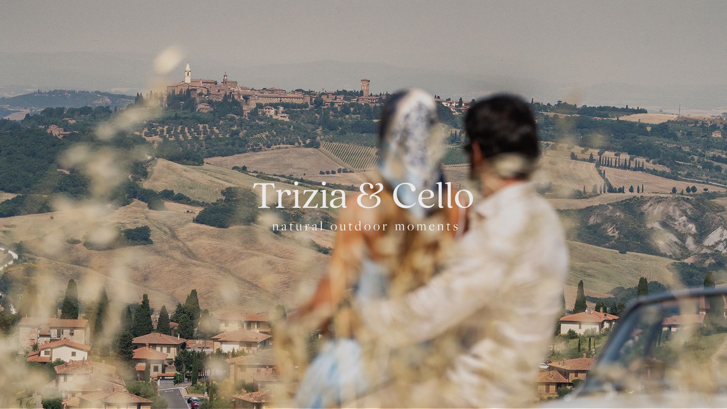 Couple embraces with Tuscan hillside village backdrop in cinematic wedding video still for Trizia and Cello.