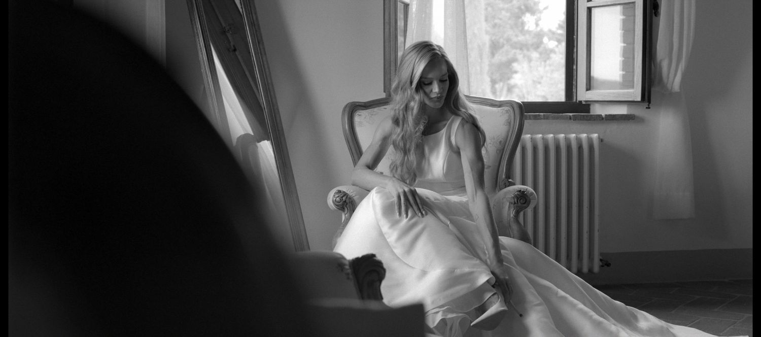 A collection of five black and white photographs showing a bride in her wedding dress during various moments of preparation.