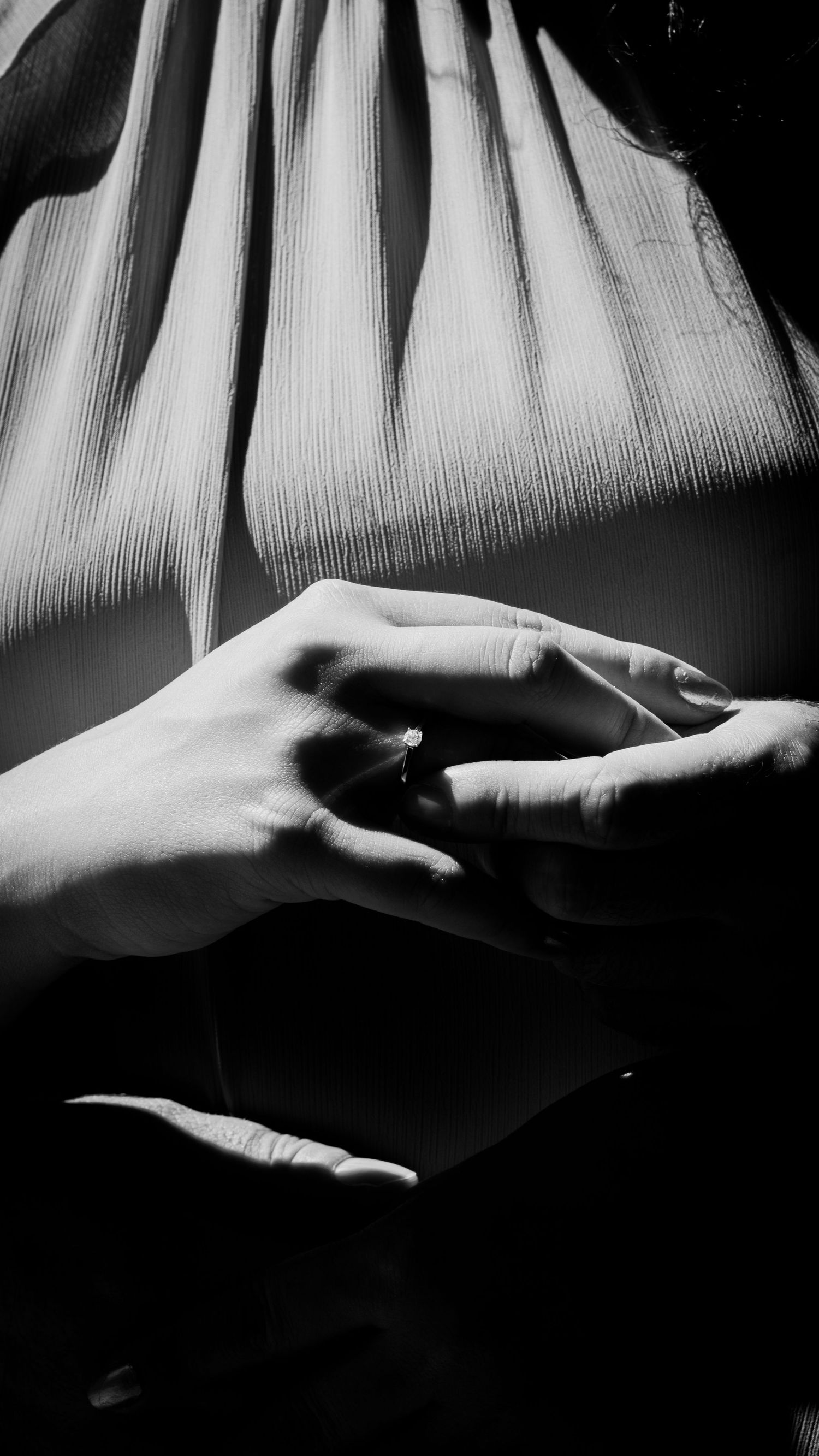 Black and white macro photography shows dramatic sequence of hands reaching and gesturing against textured backdrop.