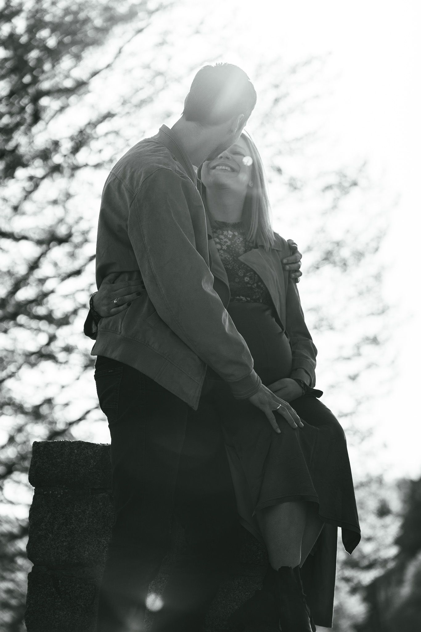 A black and white photo series showing a couple sitting close together in an intimate outdoor setting.
