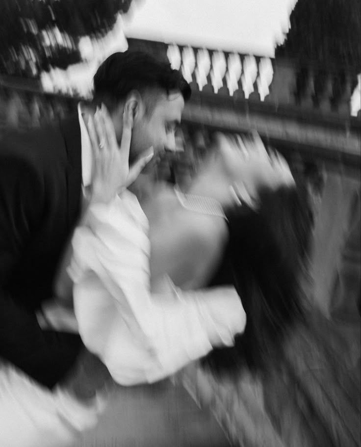 A blurred black and white motion shot of two people in an emotional embrace.