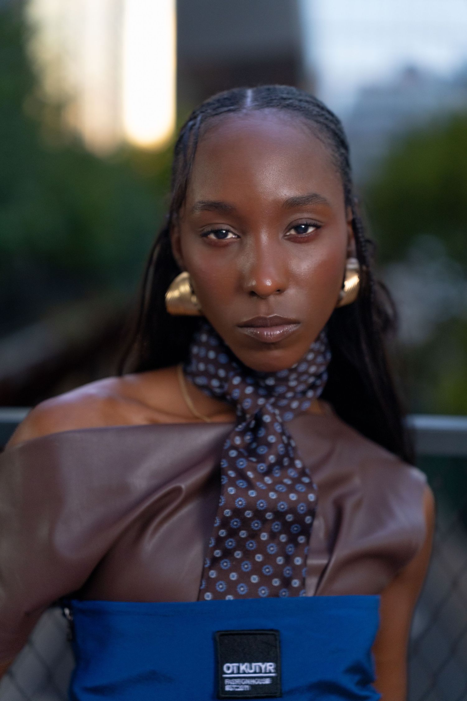 Stylish portrait featuring polka dot necktie and blue top at sunset.