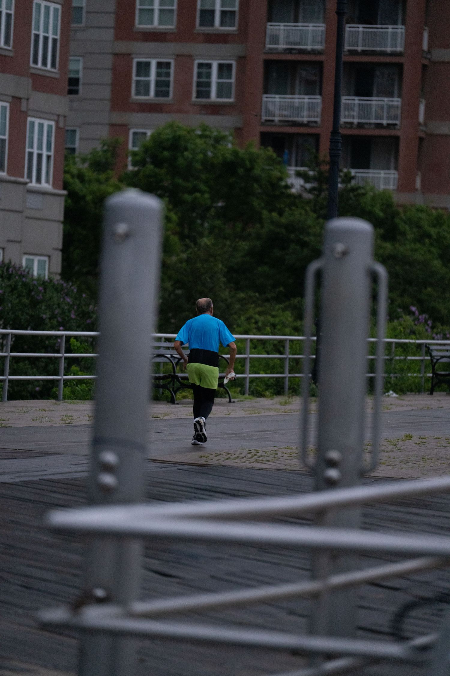 Urban skatepark with metal railings in the foreground and apartment buildings behind.