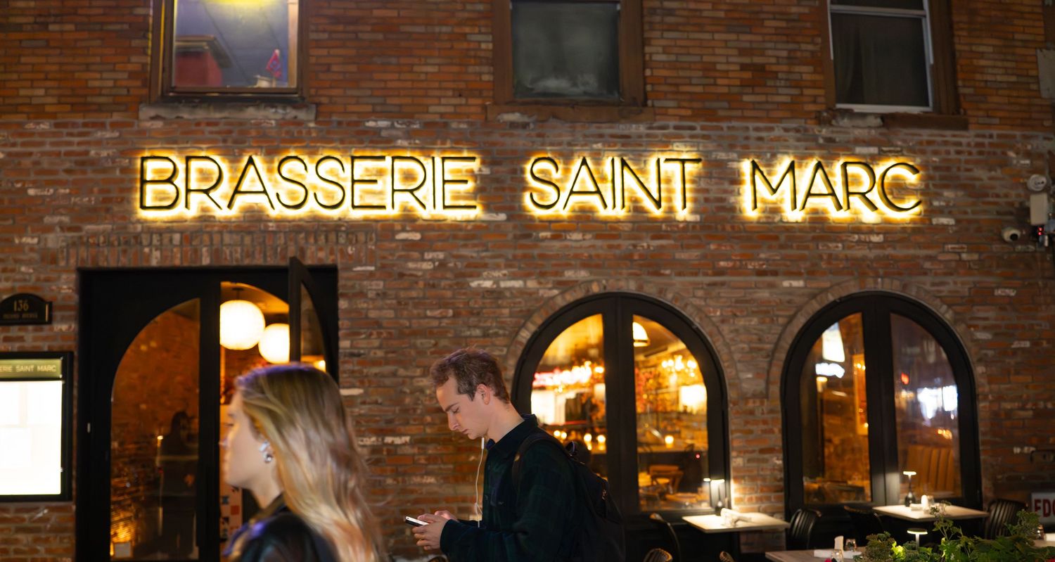 Exterior of Brasserie Saint Marc restaurant with exposed brick walls and warm lighting.