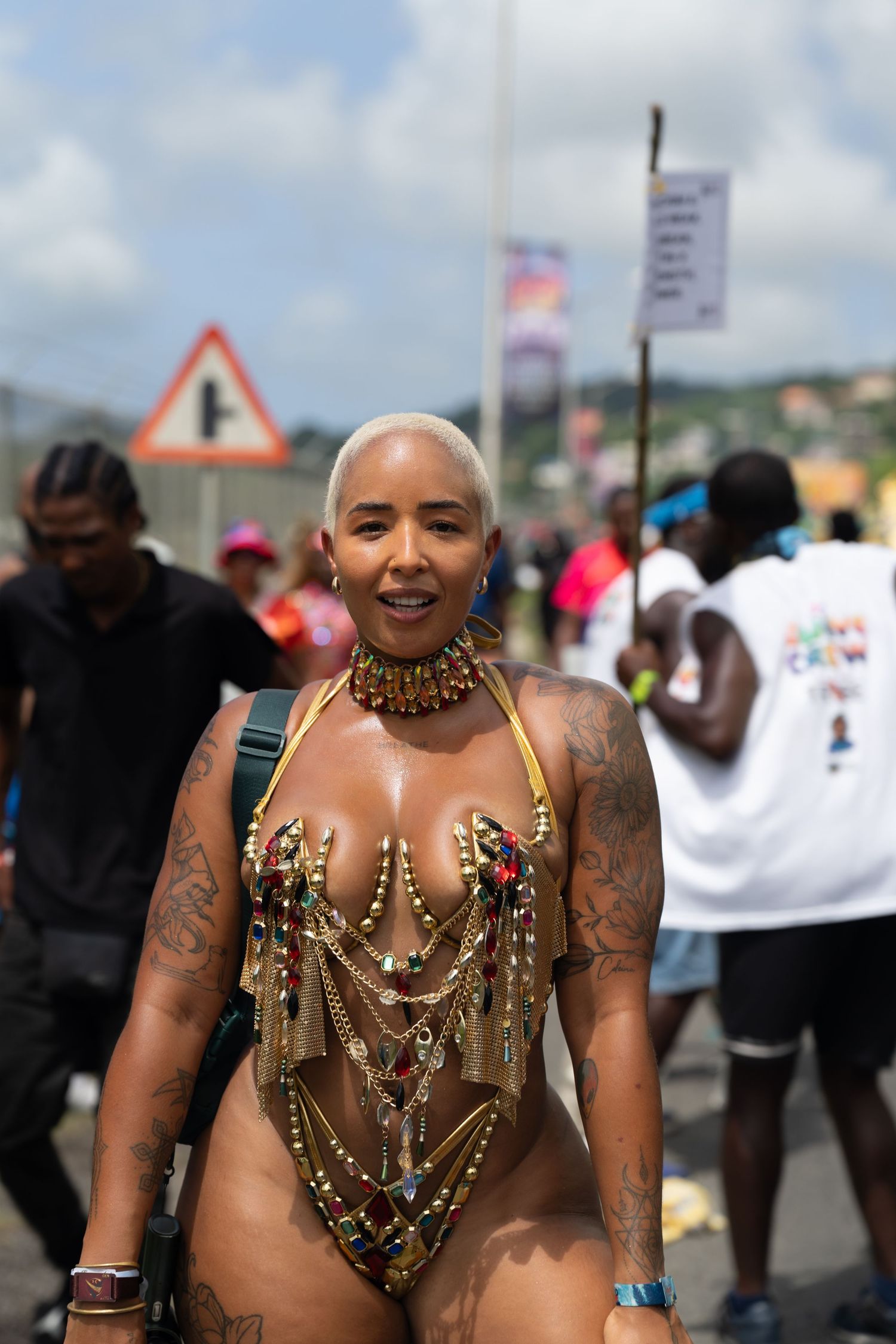 Festival participant wearing golden jewelry and body art at an outdoor celebration.