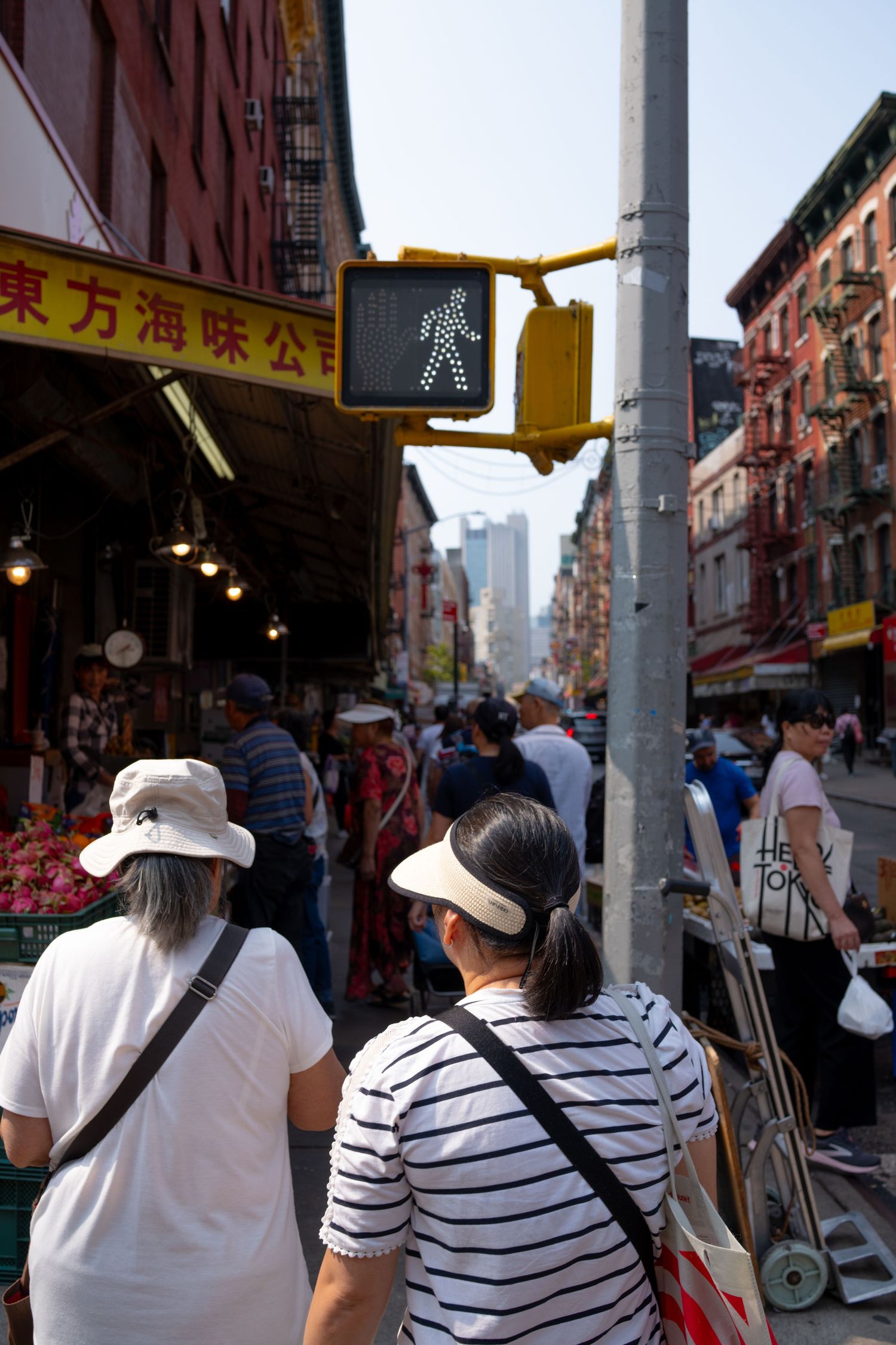 Tourists walking down busy Chinatown street with storefronts and Chinese signage visible.