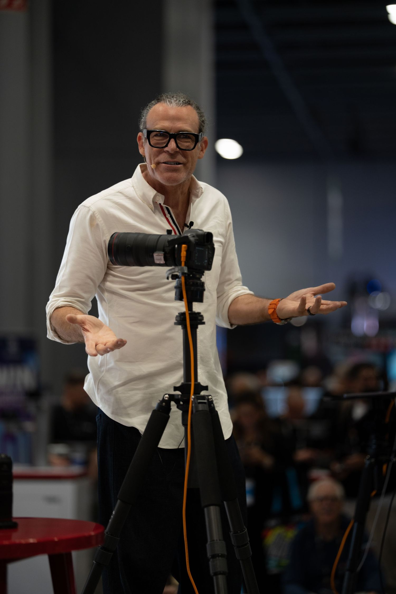 Performer in white shirt and black pants gestures expressively on stage.