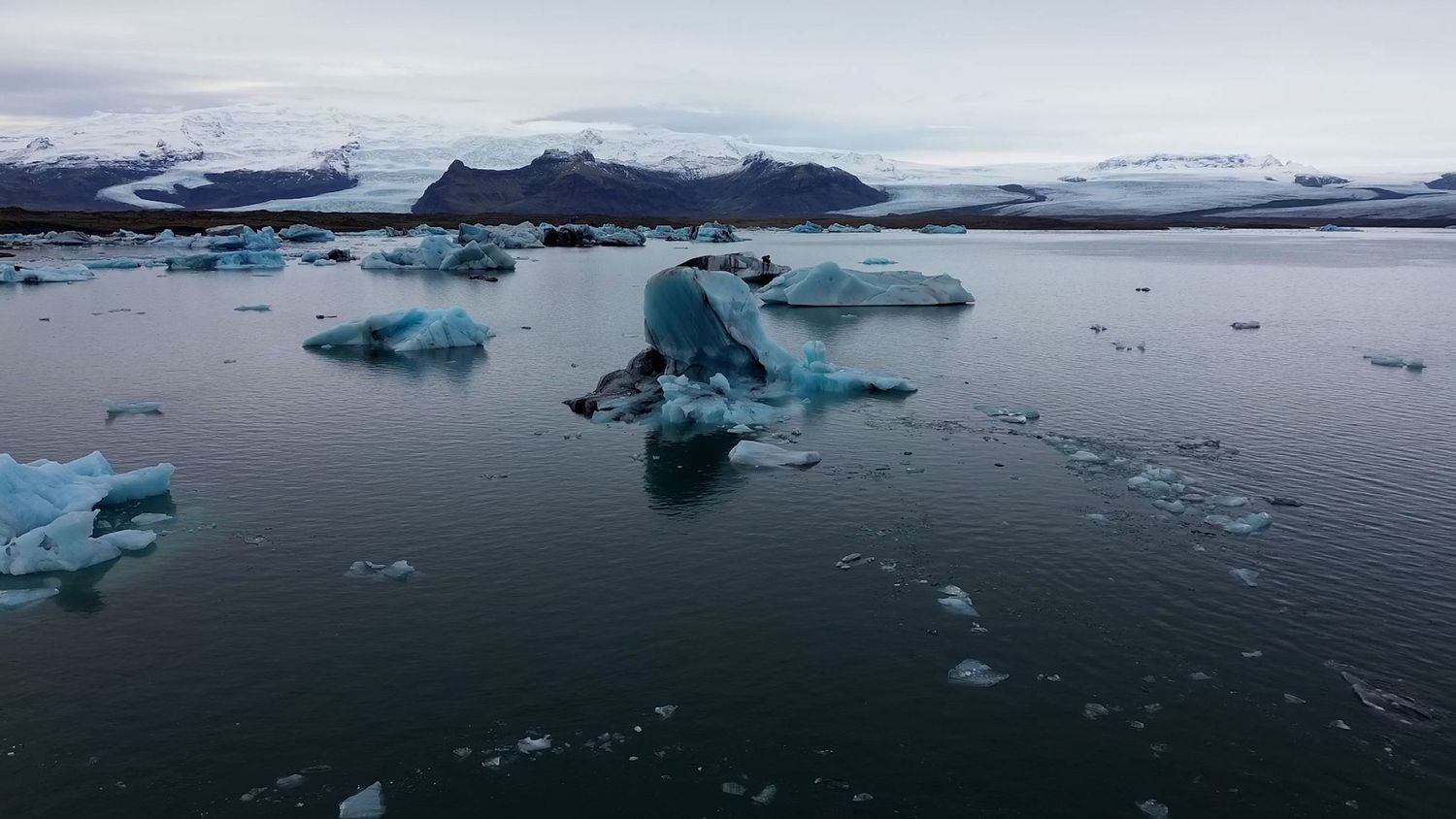 Panoramic view of icebergs floating in arctic waters against a cloudy sky.