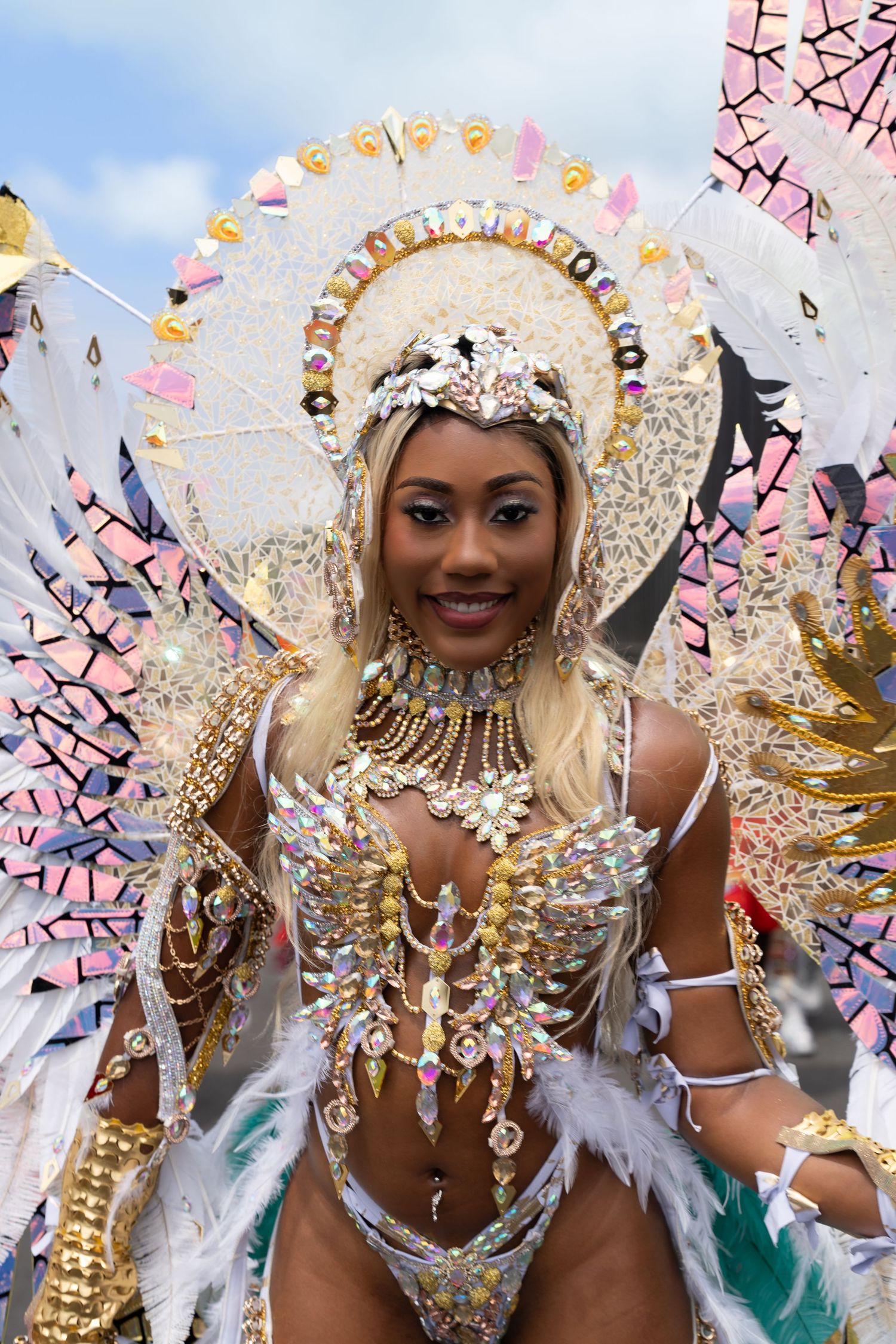 Performer in a dazzling white and gold carnival costume with feathers and crystals.