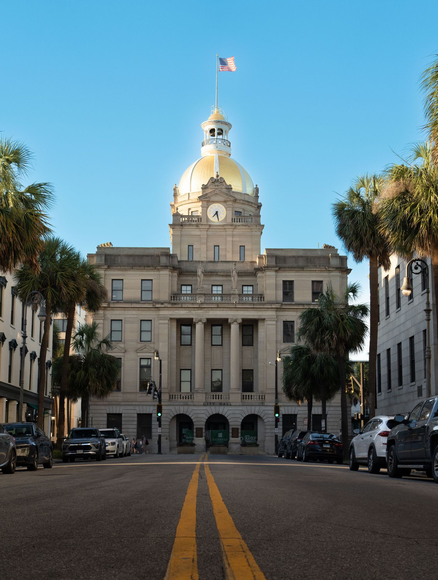 Historic government building with golden dome and palm trees in classical architectural style.