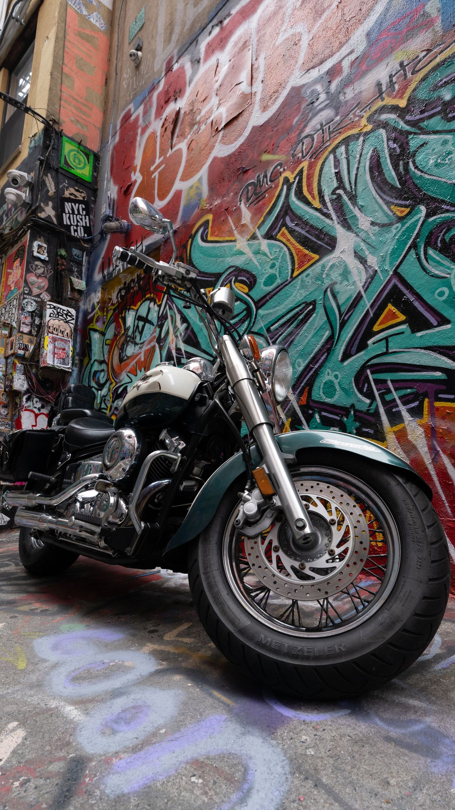 Motorcycle parked against a wall covered in colorful graffiti artwork.