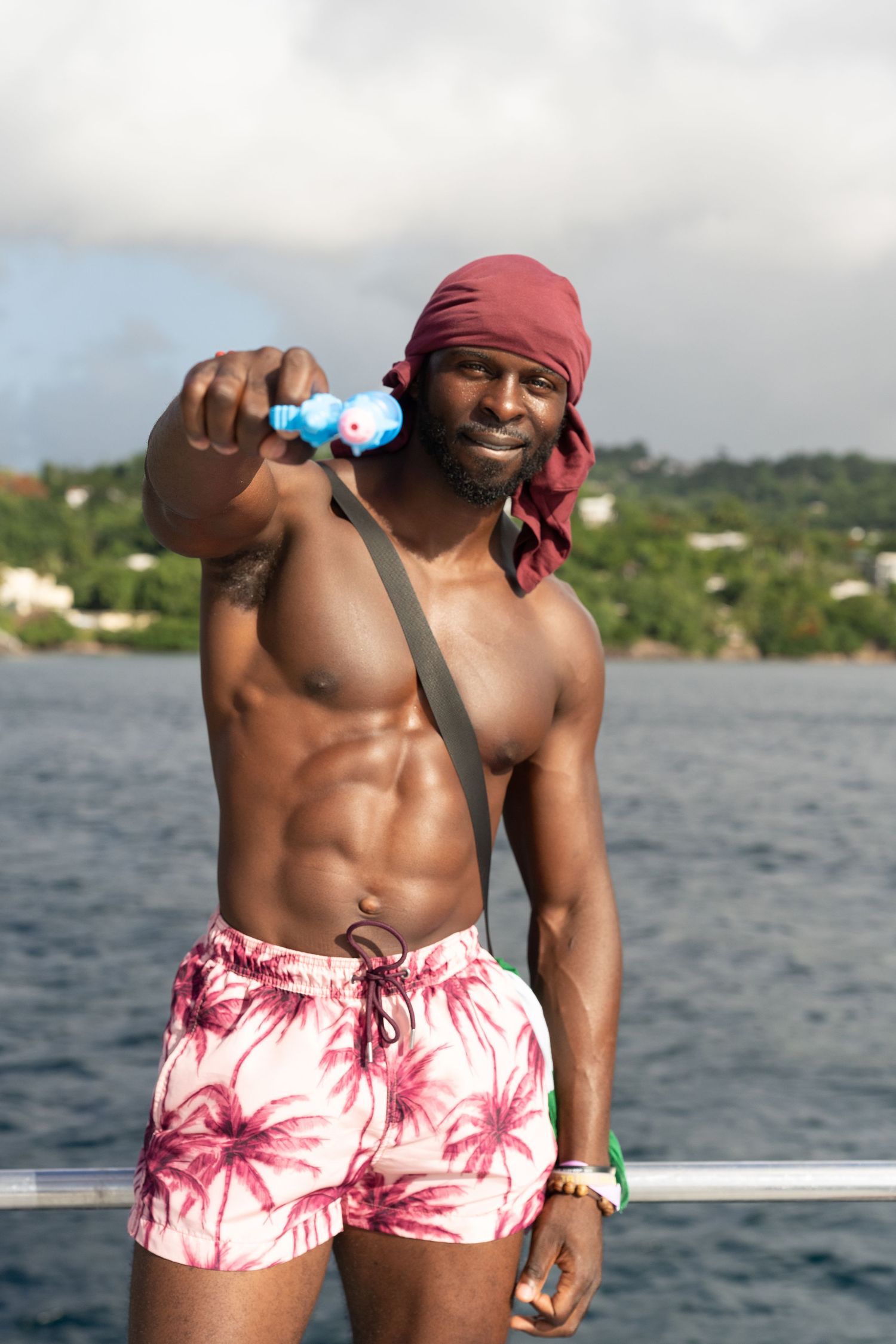 Person in pink tie-dye swim shorts and bandana enjoying time on a boat.