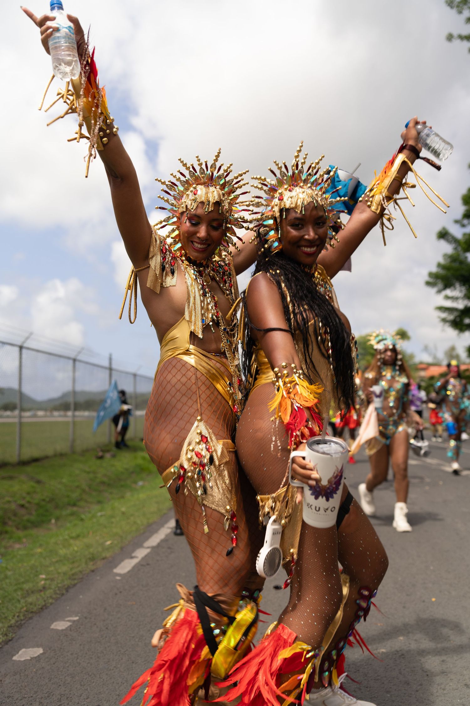 Carnival performers in vibrant gold and red costumes dancing at an outdoor festival.