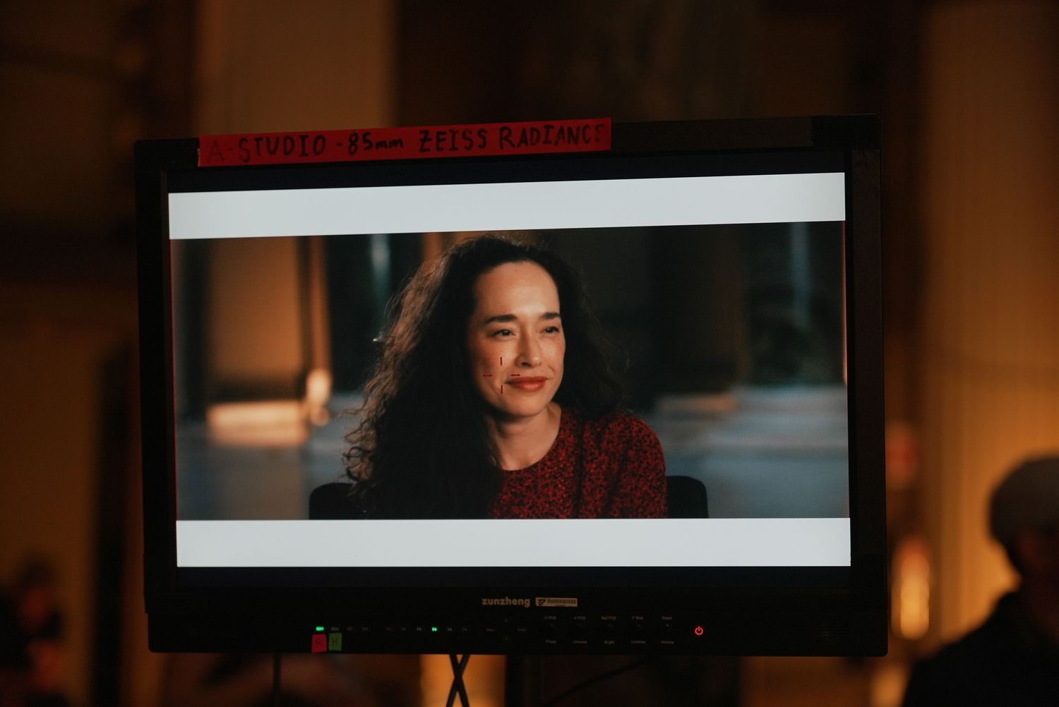 A dimly lit scene showing a person speaking during what appears to be a film or video production.
