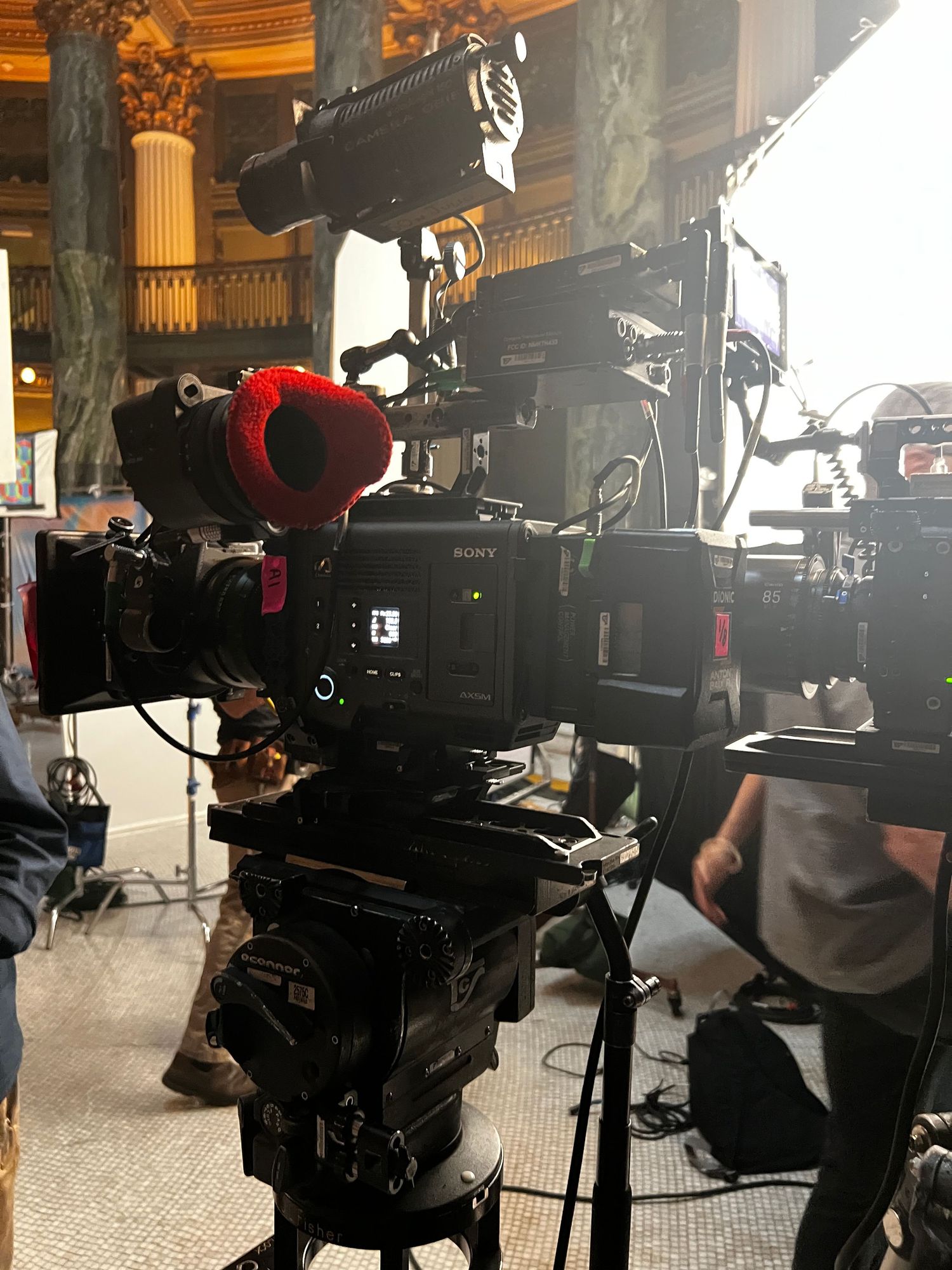 Professional video camera equipment set up on tripods in an ornate indoor venue.
