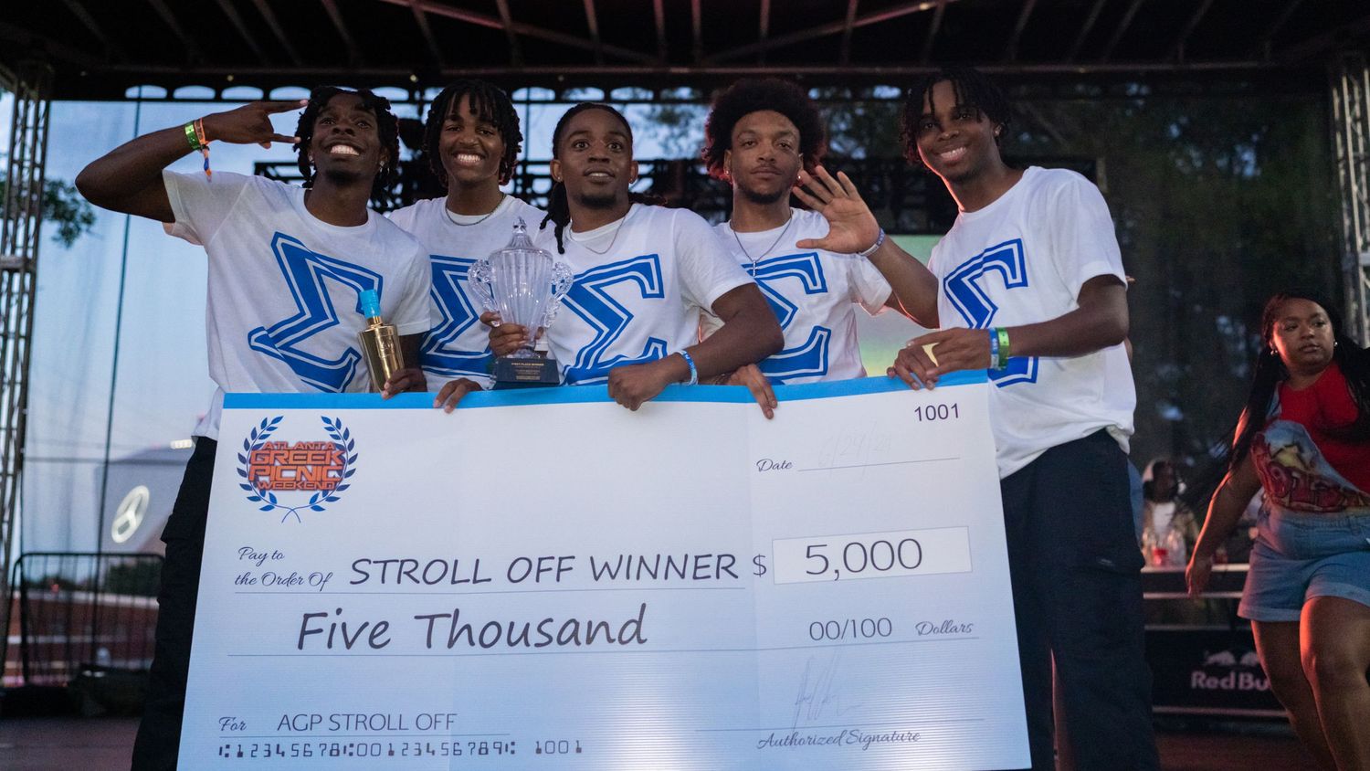 Large group displaying oversized prize checks at an outdoor event.