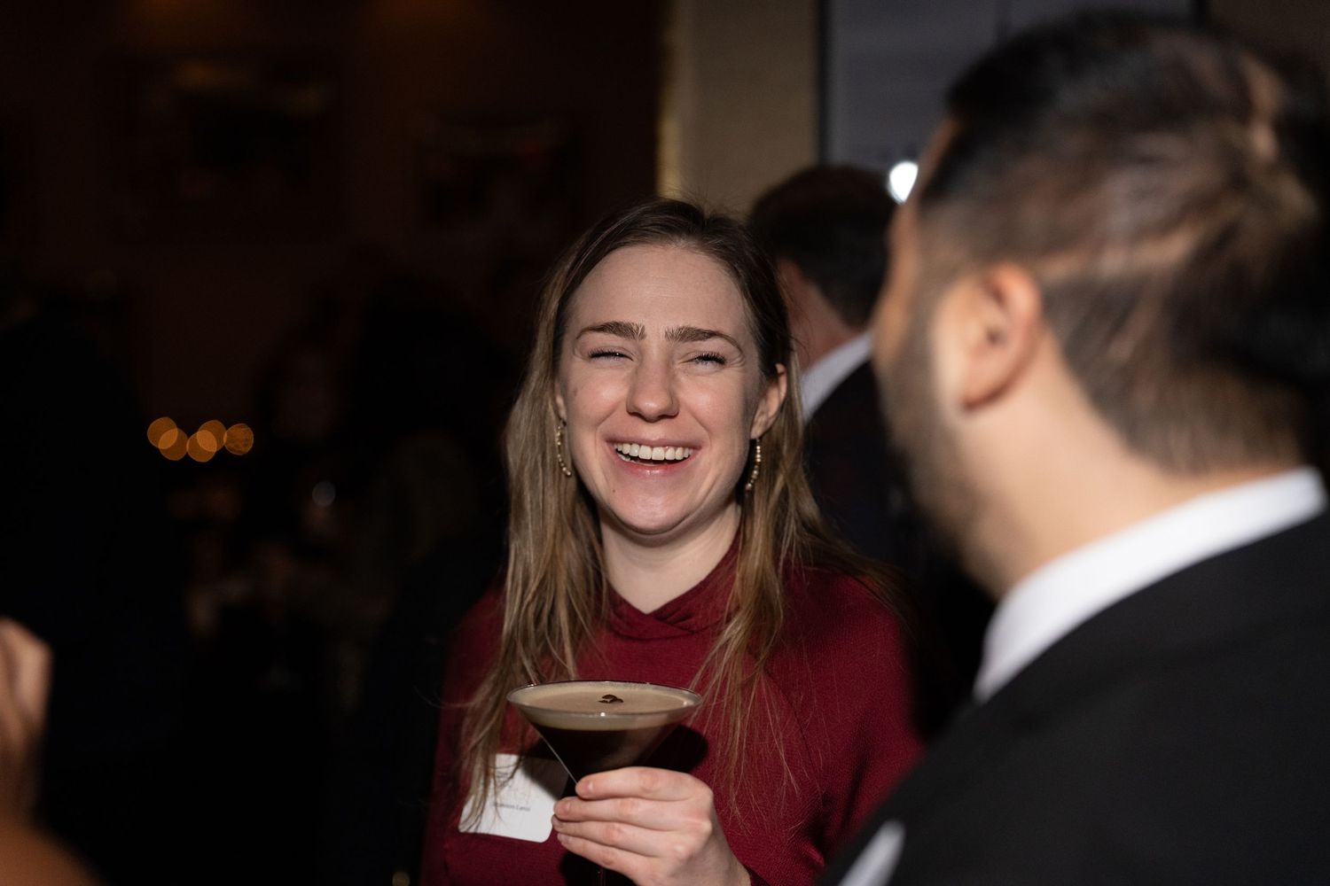 A sequence of candid moments showing laughter and conversation between people in a dimly lit setting.