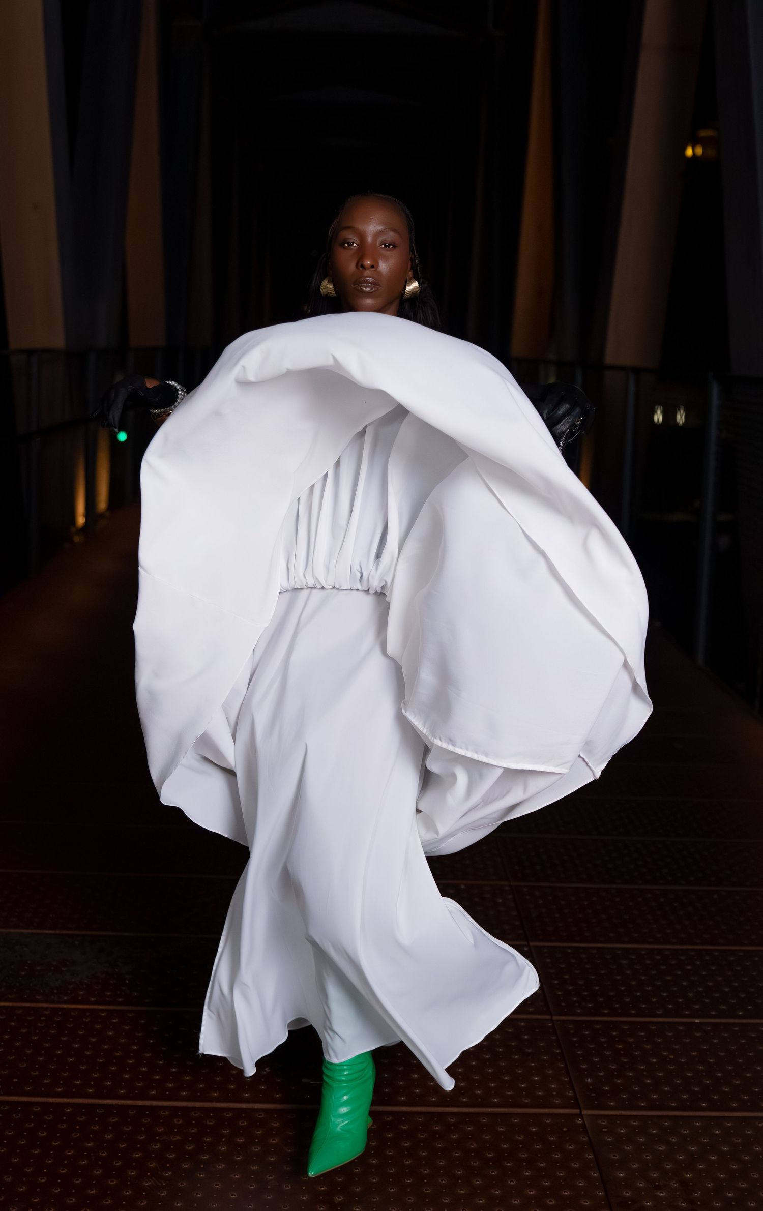 Flowing white dress movement captured against dark floor with bright green shoes visible.