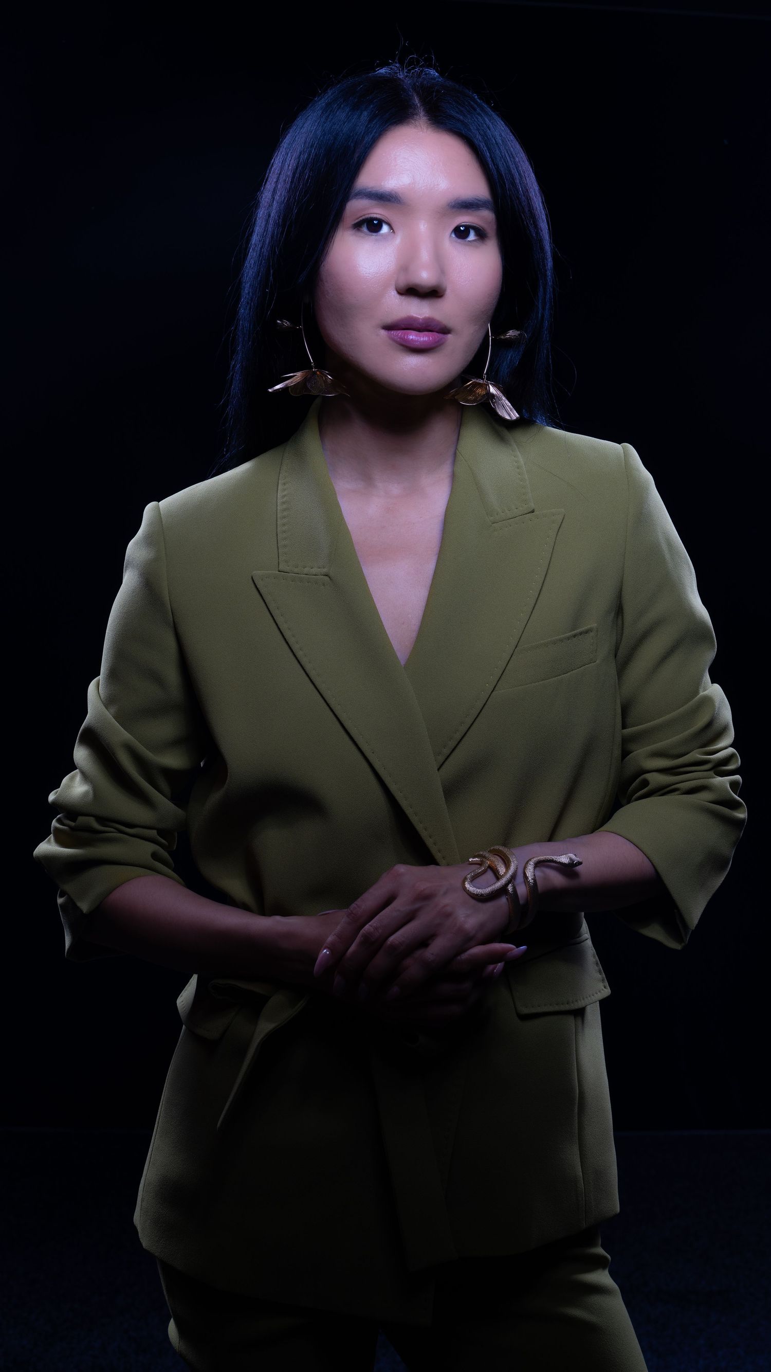 Artistic fashion photo of model in oversized olive blazer with dramatic shadows.
