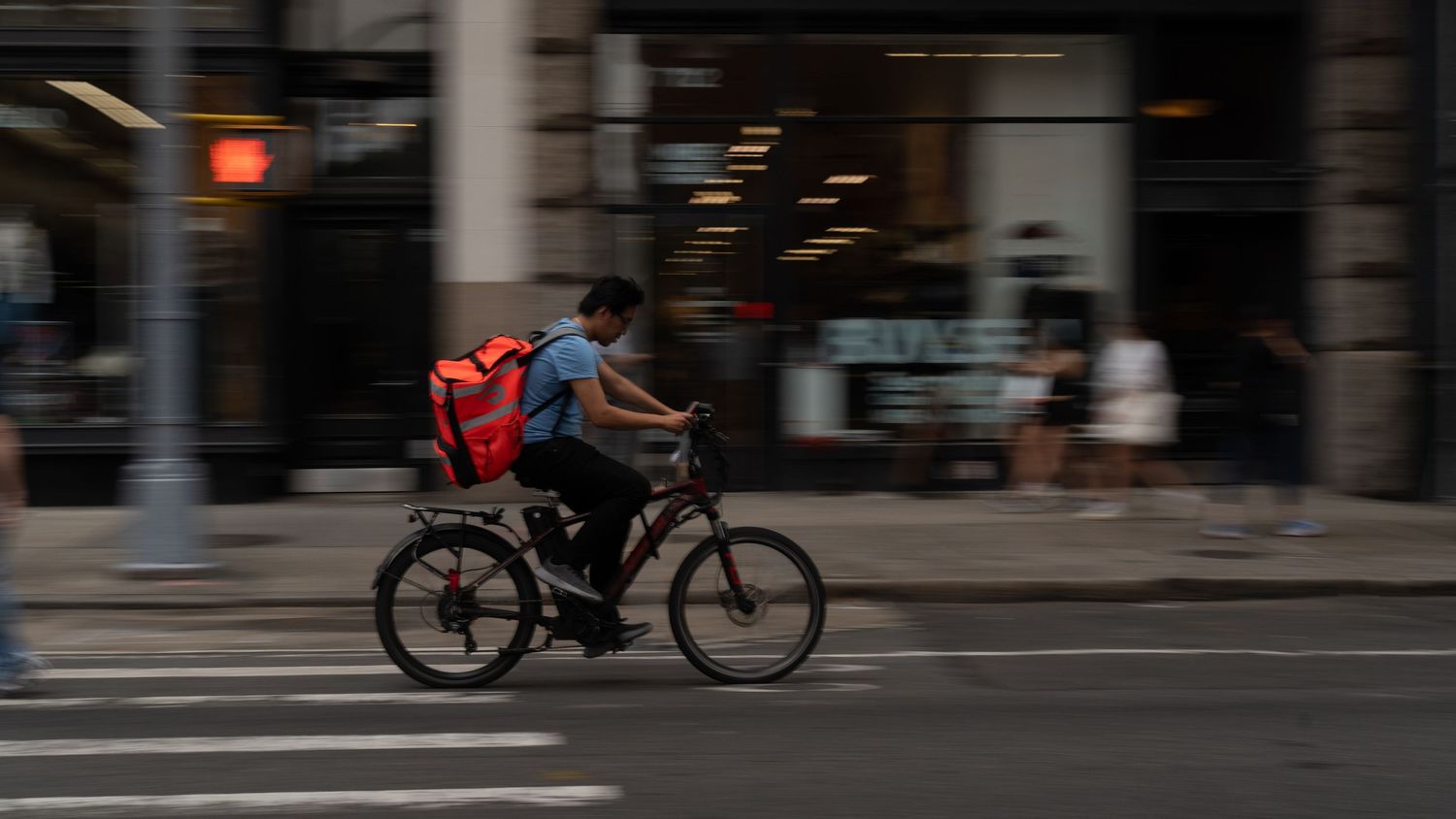 Blurred urban street scene with cyclist and vehicles in motion.