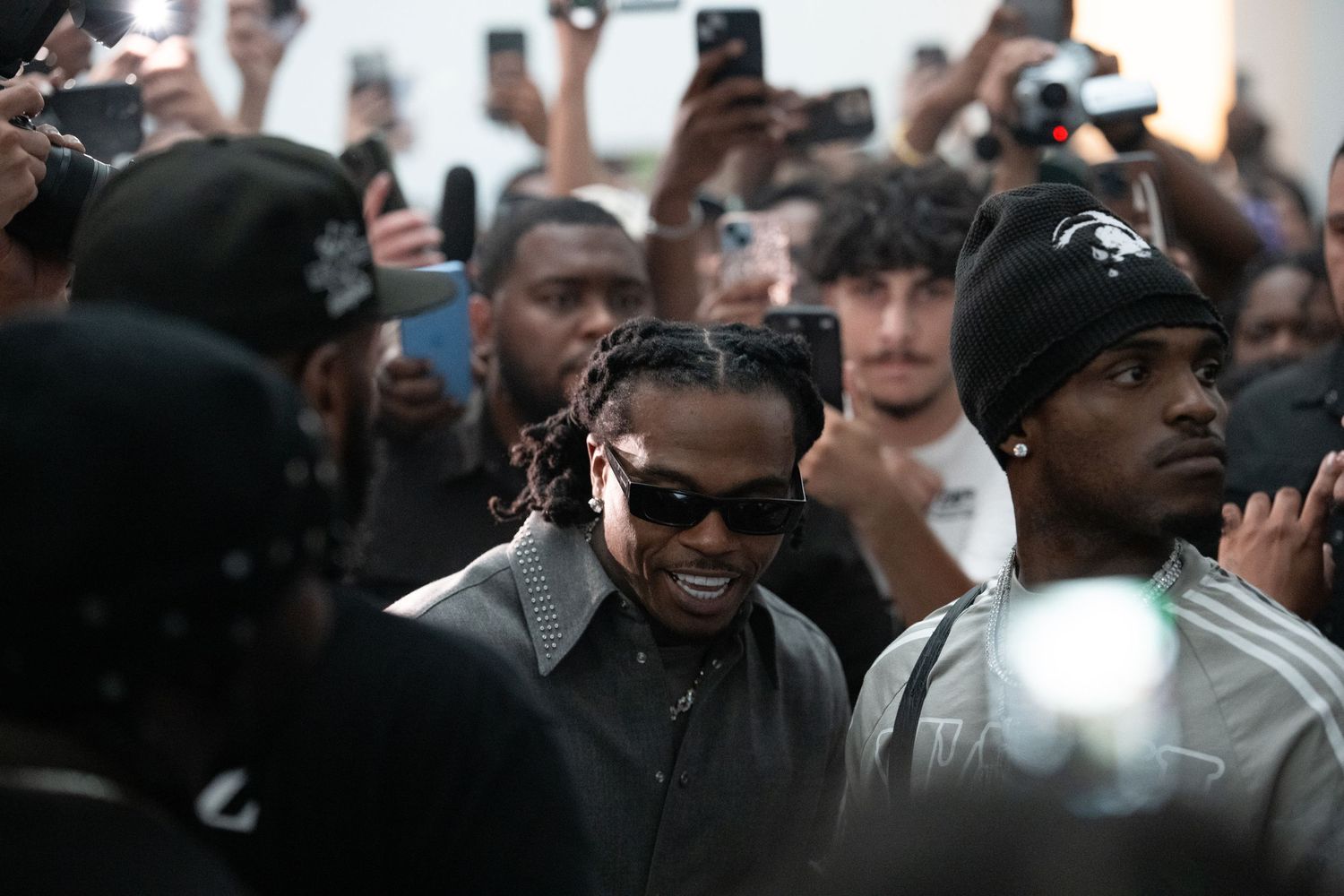 Crowd gathering at an event with phones raised to capture photos and video.
