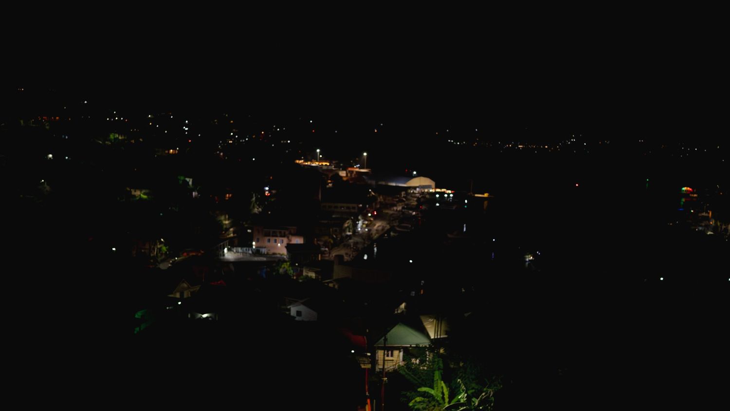 Nighttime cityscape showing scattered lights across a dark horizon.