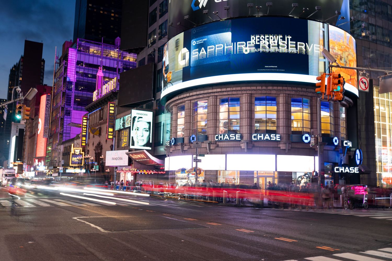 Wide angle shot of Times Square's illuminated commercial displays and digital screens at night.