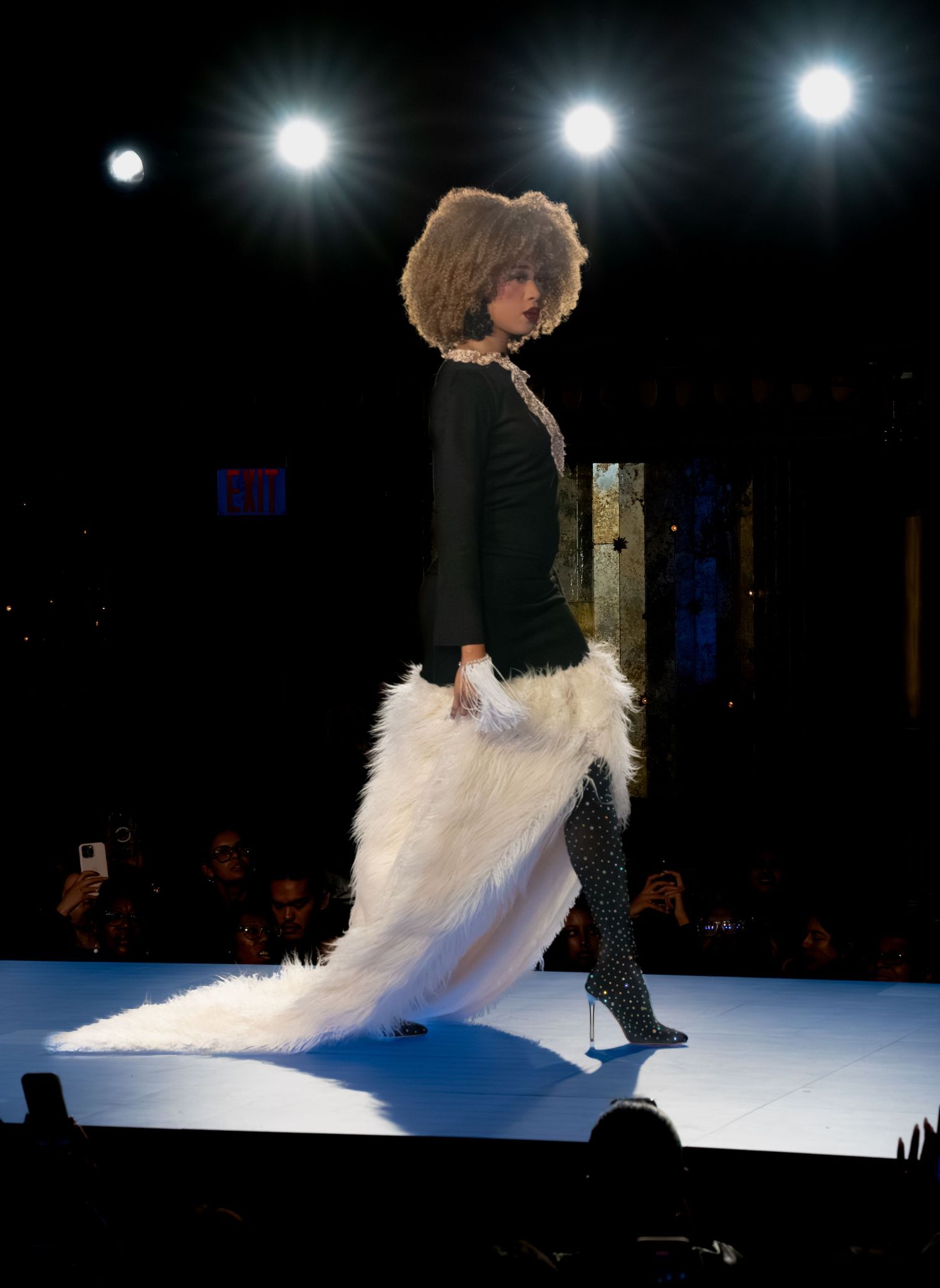 Performer in black and white outfit twirls on illuminated stage.