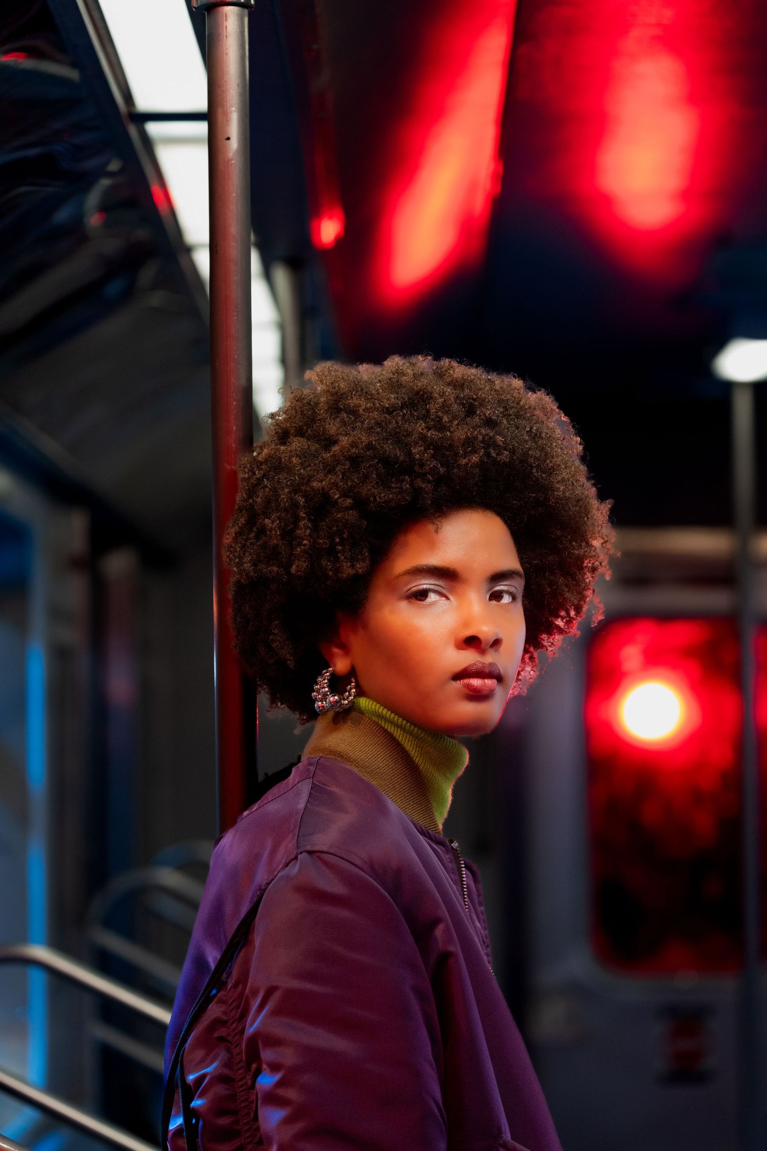 Portrait in purple lighting with curly hair and dramatic red illumination.