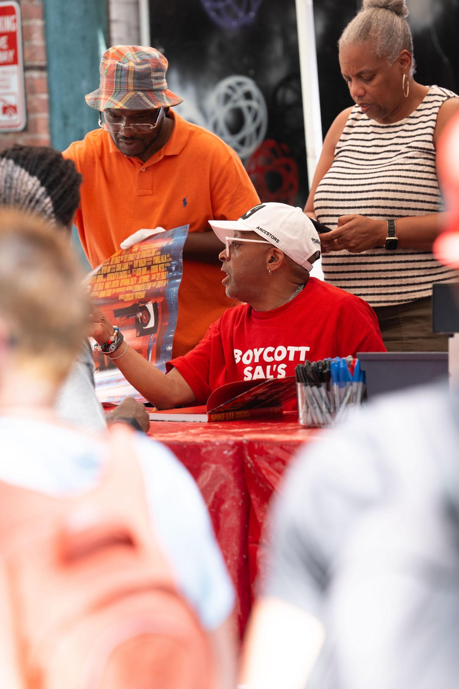 People gathered outdoors wearing red and orange shirts at what appears to be a public event.