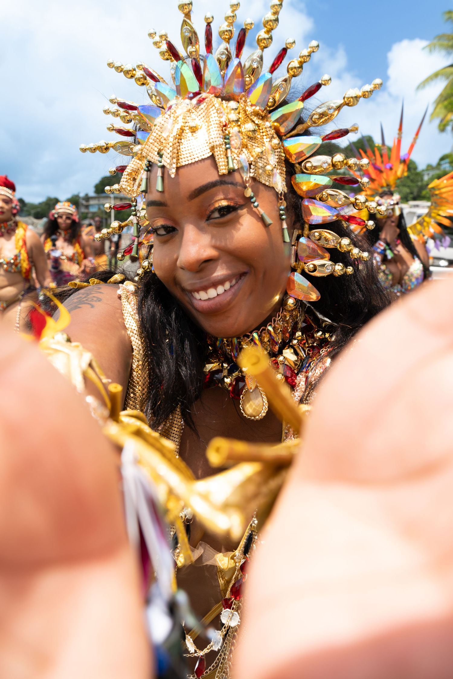 Carnival performer wearing a golden spiked crown and festive decorations celebrates during a parade.
