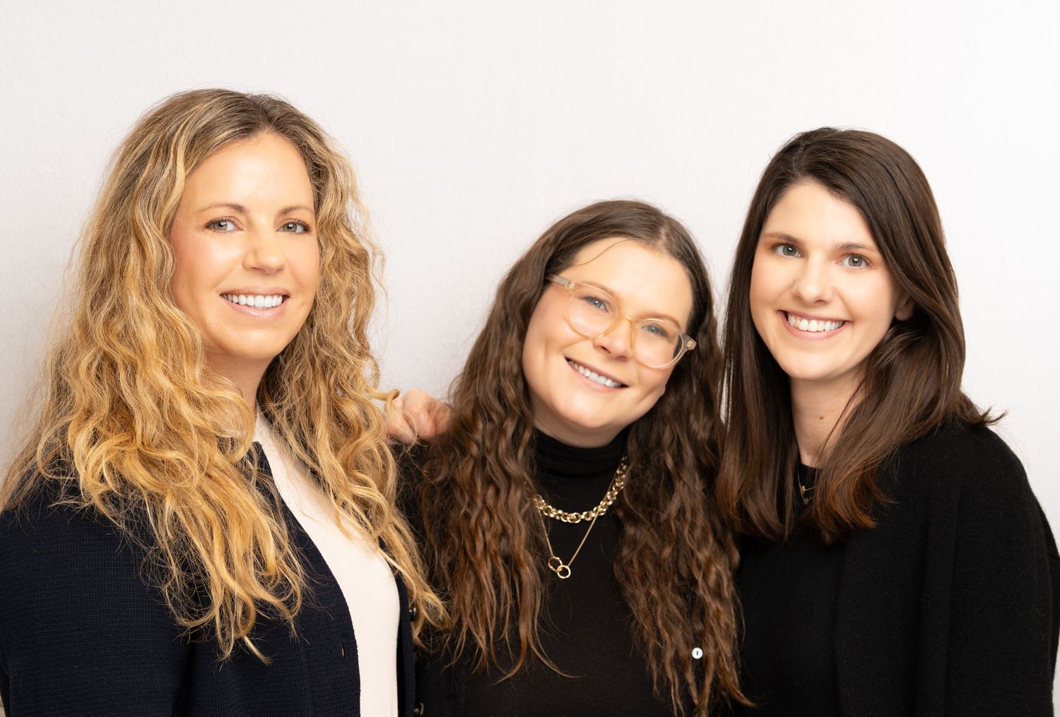 A group of women with long hair pose together smiling at the camera in a series of connected photos.