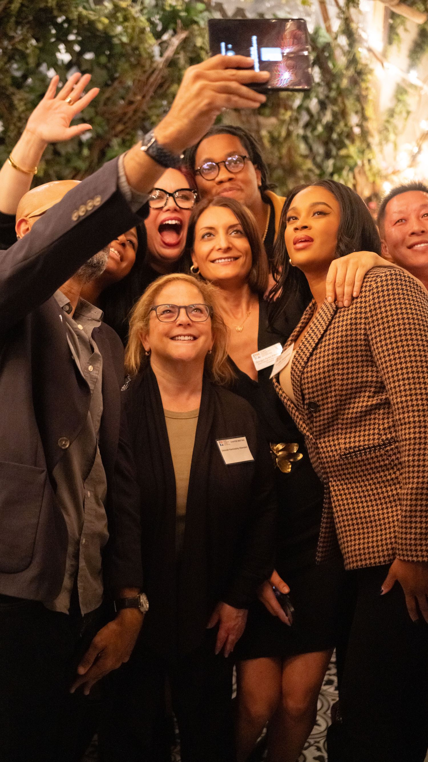 Enthusiastic group taking selfie together at social gathering.