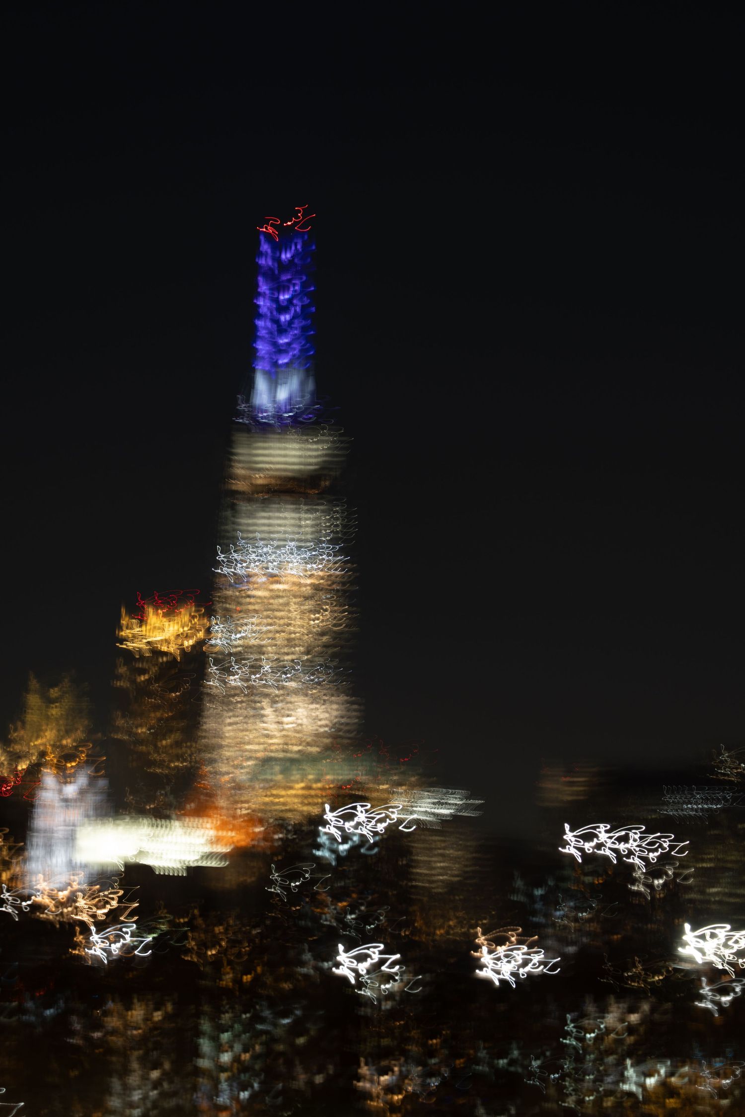 Blurred cityscape at night with illuminated skyscraper lights creating an abstract effect.
