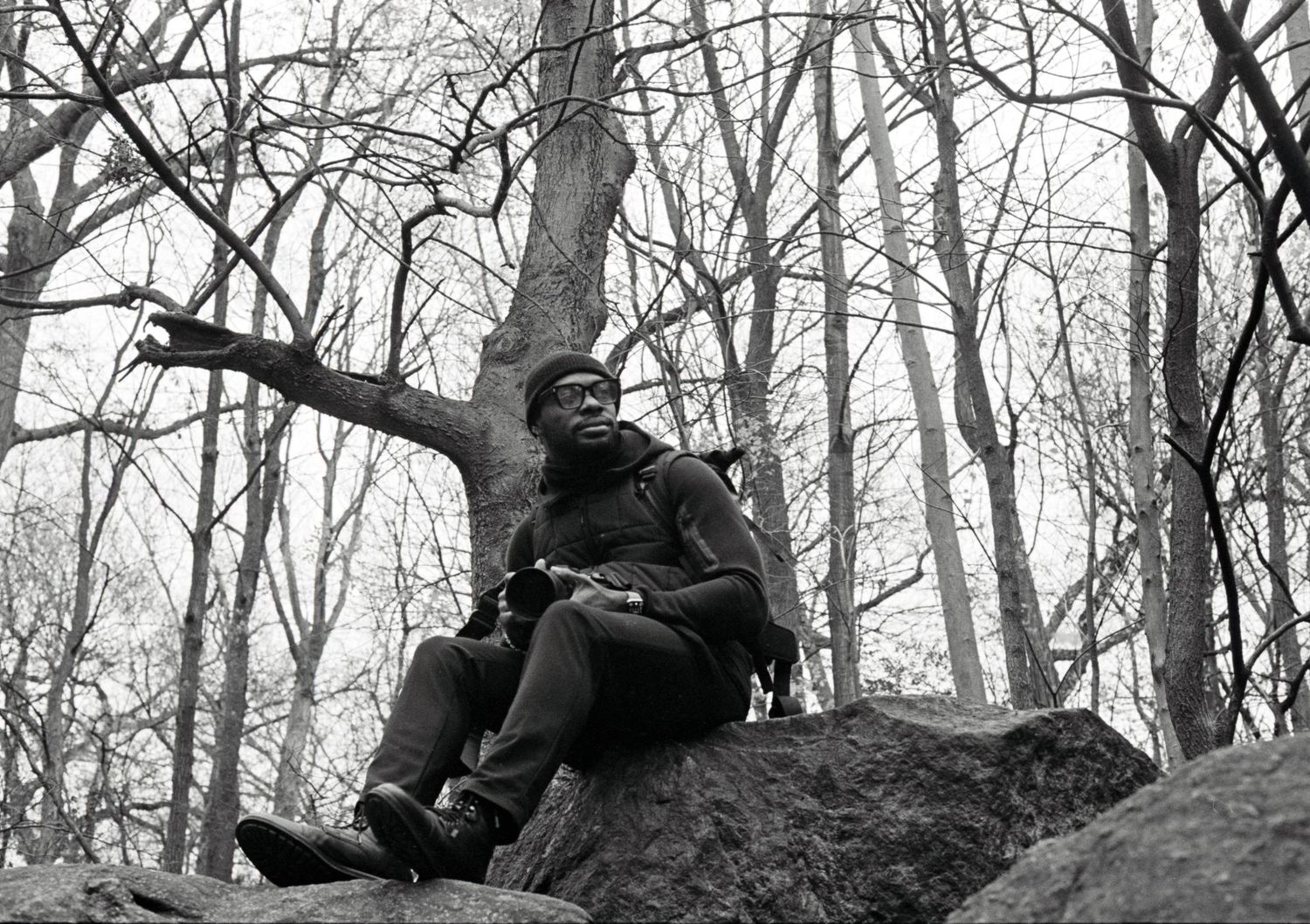 Civil War soldiers in uniform take defensive positions behind rocks in a wooded area during battle reenactment.