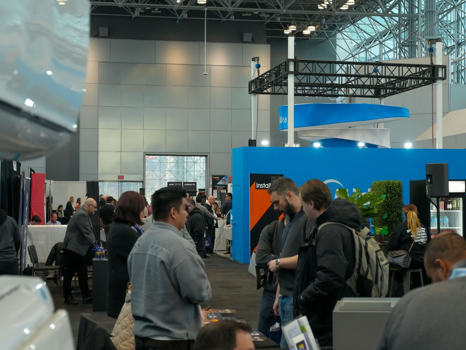 Attendees networking at a busy tech conference expo hall with blue branded booths and displays.