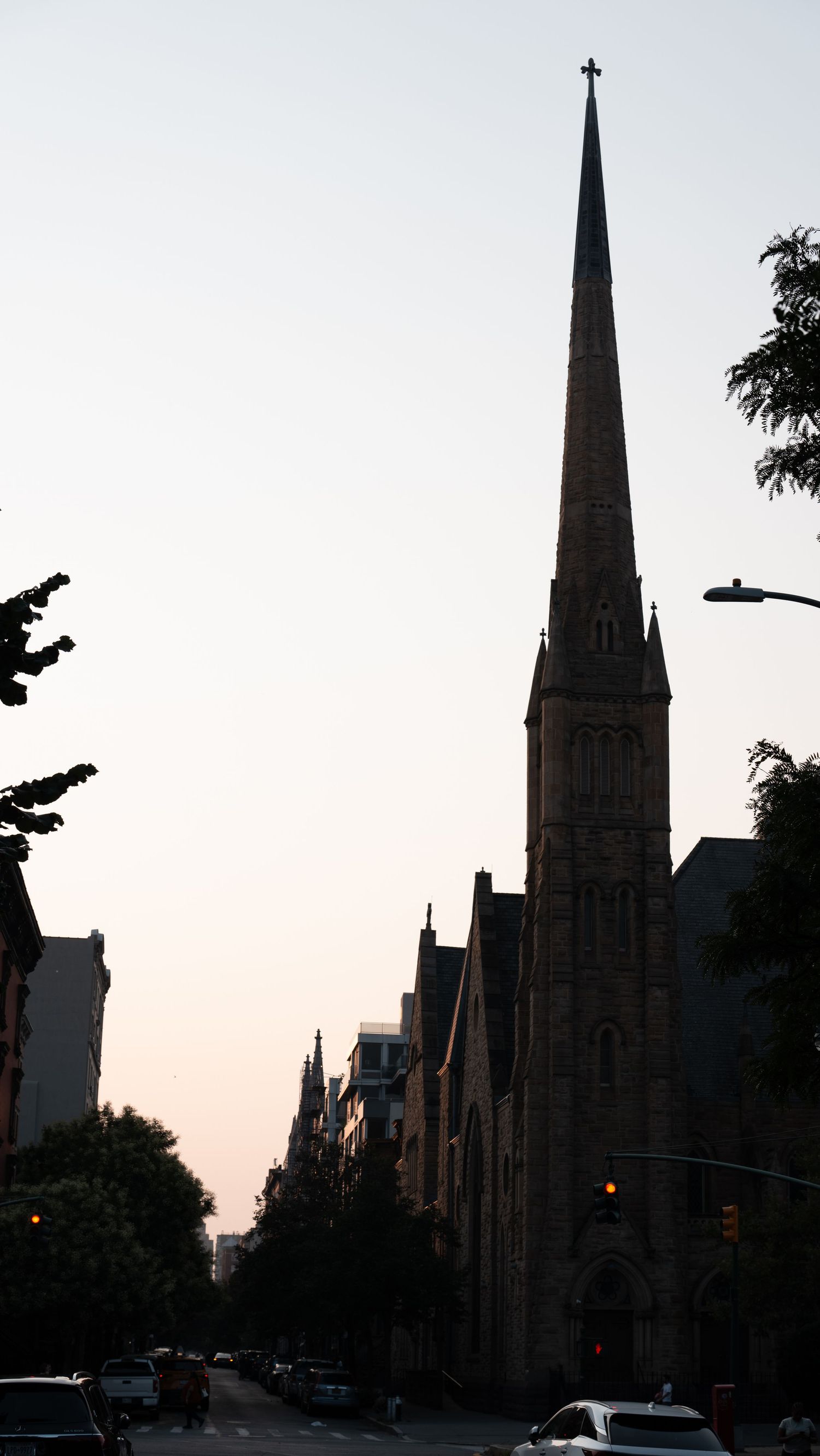 Gothic church spires silhouetted against a dusky sky in an urban setting.