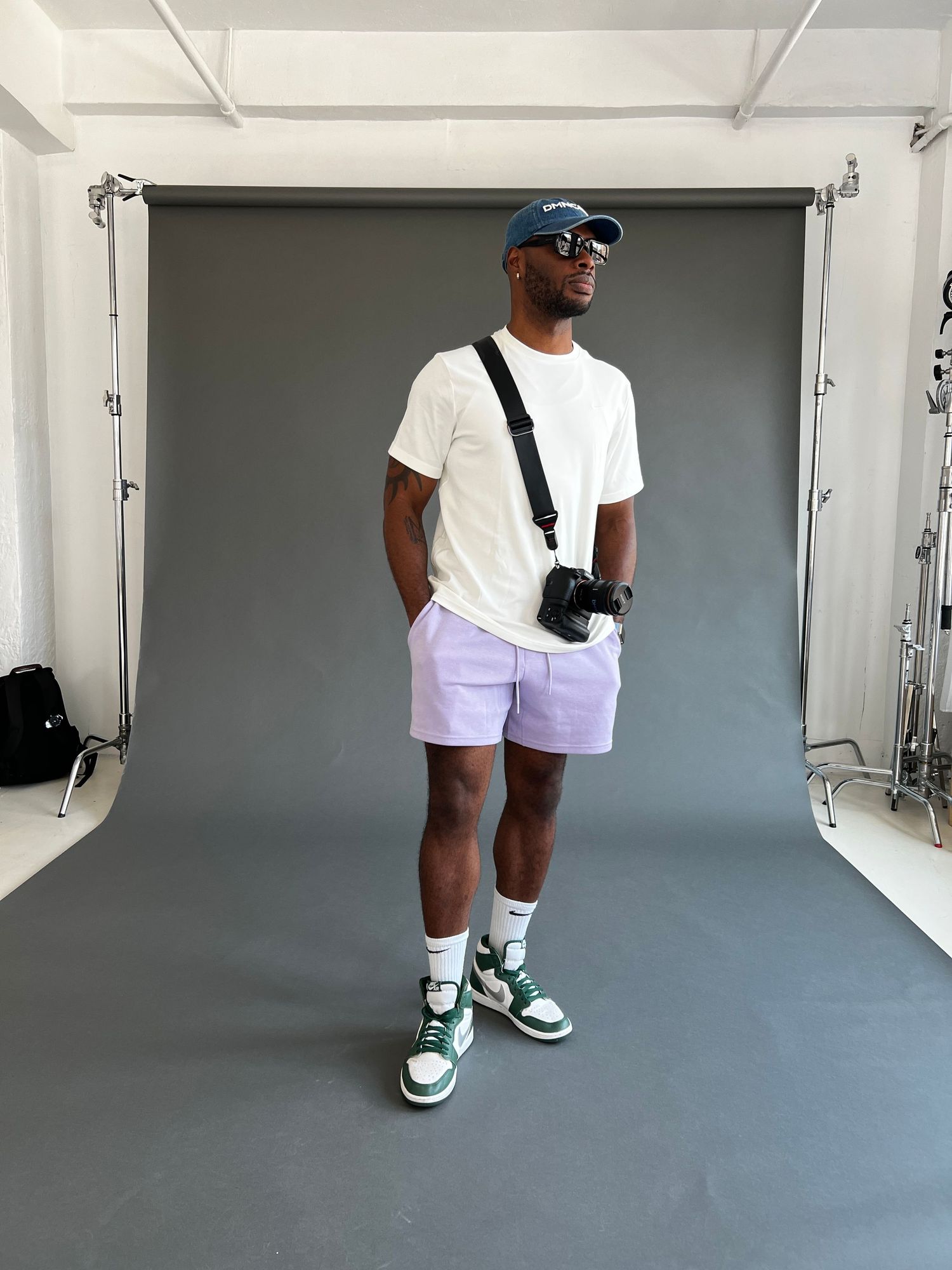 Person wearing white outfit and green sneakers walking in a studio space.