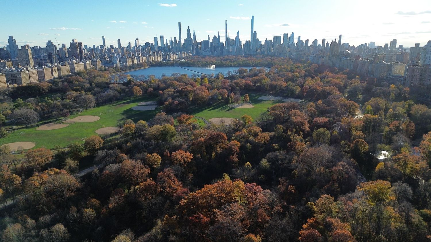 Aerial view of Central Park in autumn with colorful fall foliage and Manhattan skyline in the background.