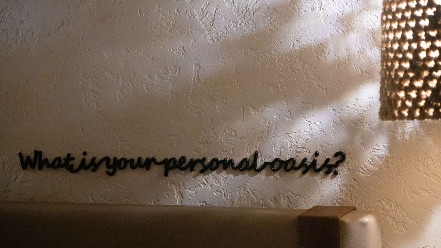 Wall text art asking 'what is your personal cost?' with decorative lighting.