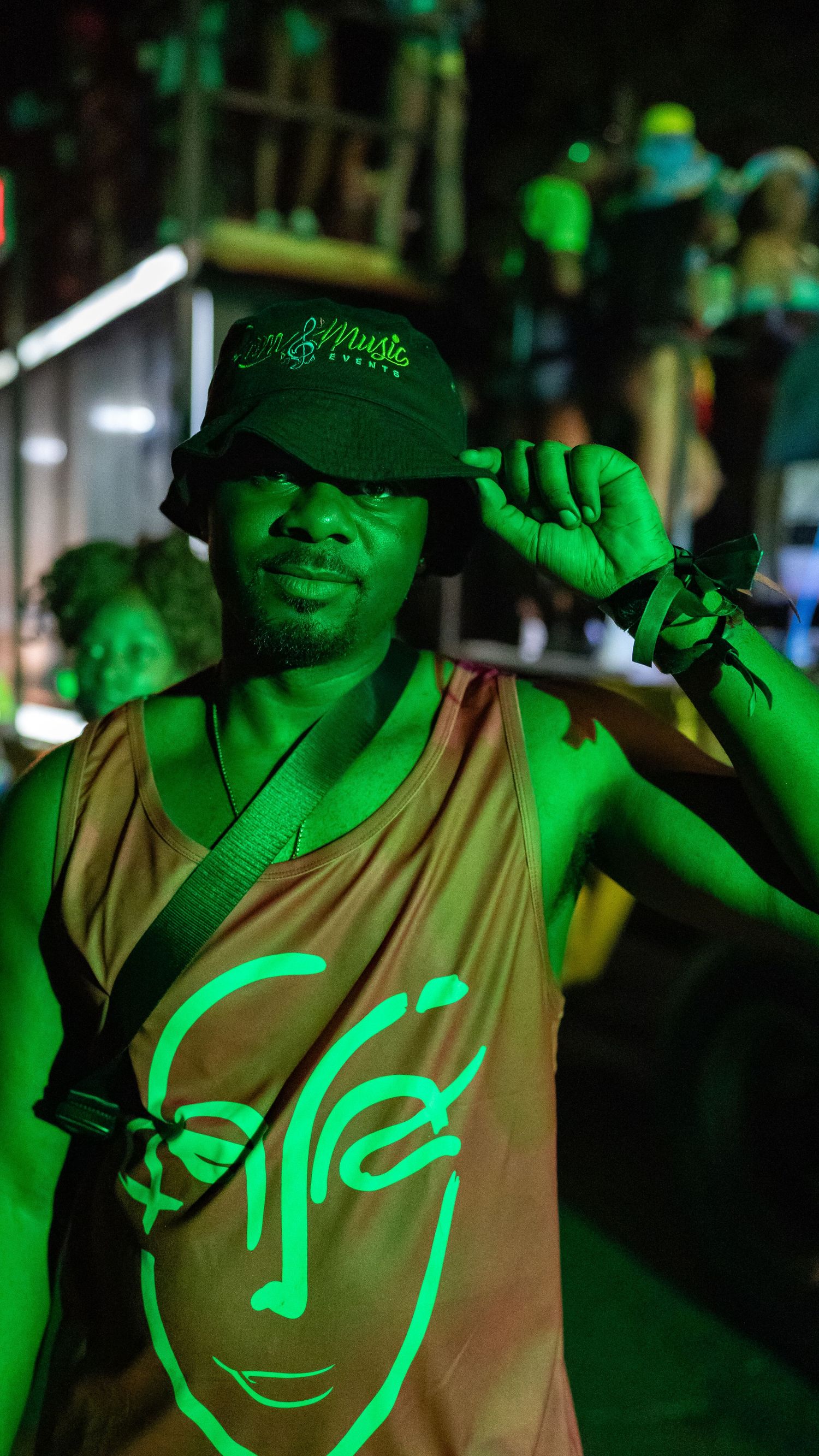 Event attendee in tan vest illuminated by green stage lighting at night.