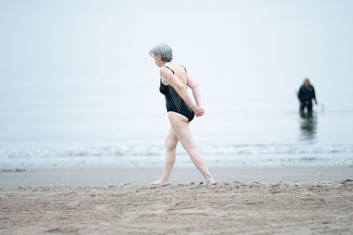 Misty beach scene with silhouettes walking along the foggy shoreline.