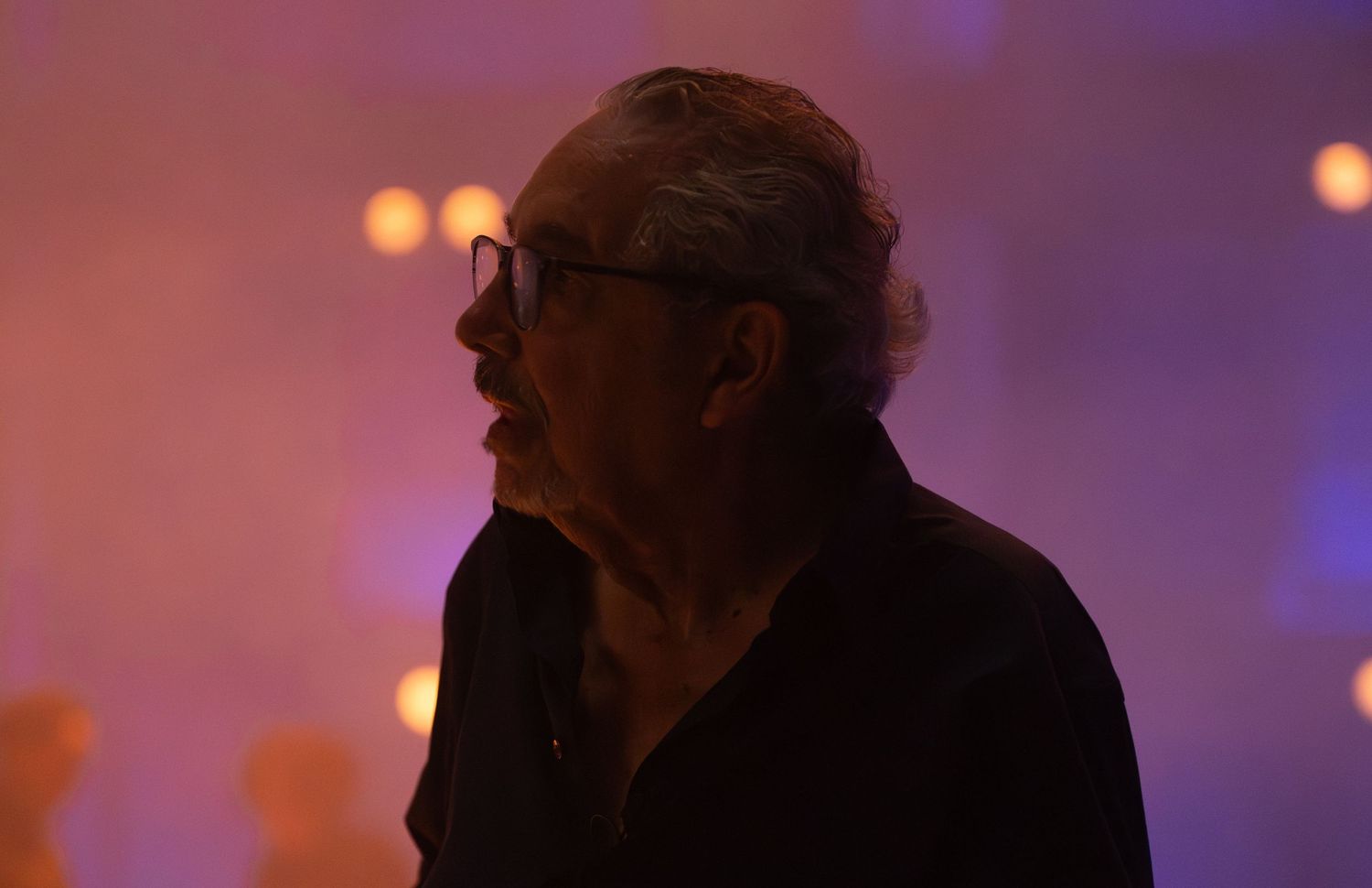 Purple and orange stage lighting creates an atmospheric ambiance during an indoor event.