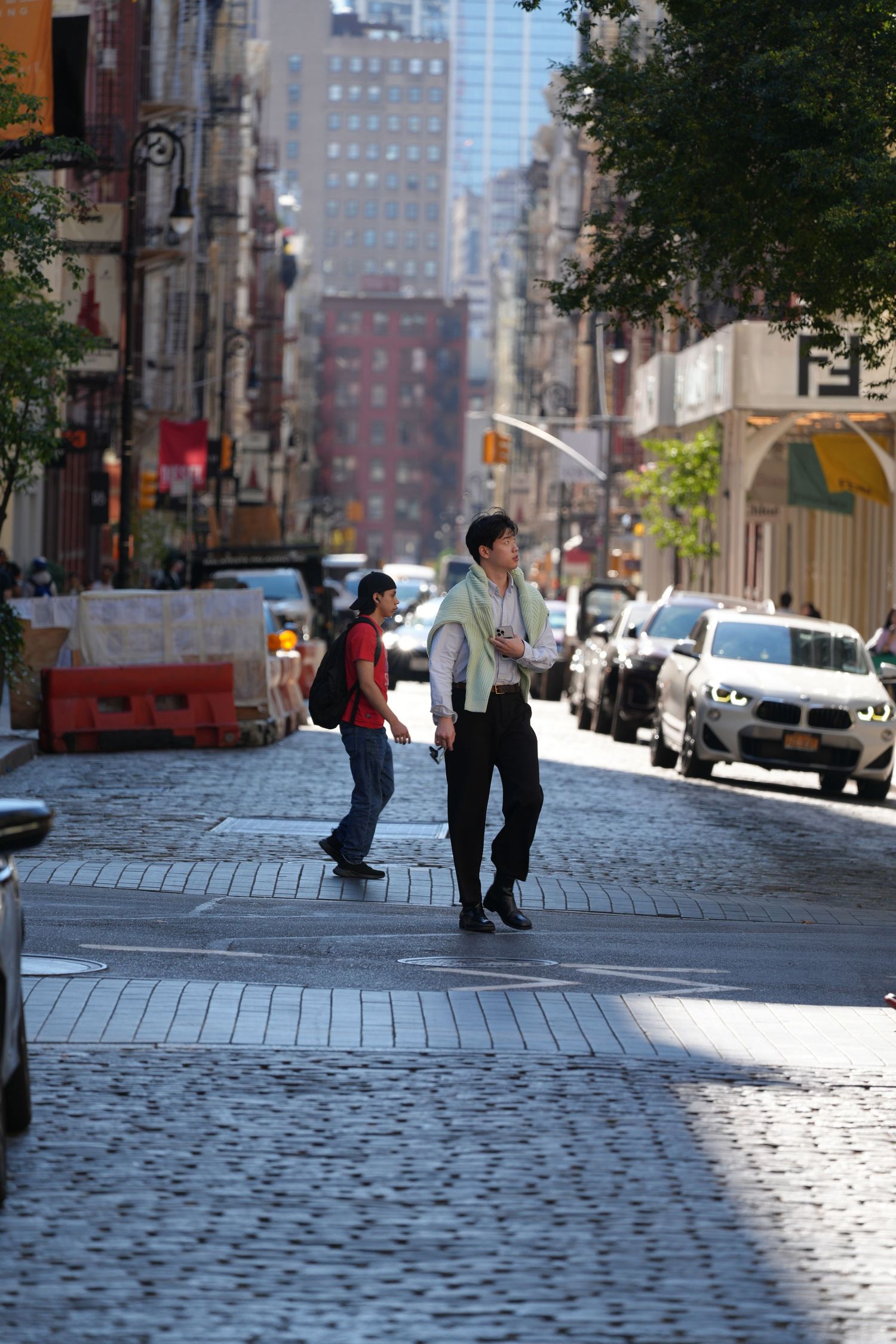 Sun-dappled cobblestone street between historic buildings in an urban neighborhood.