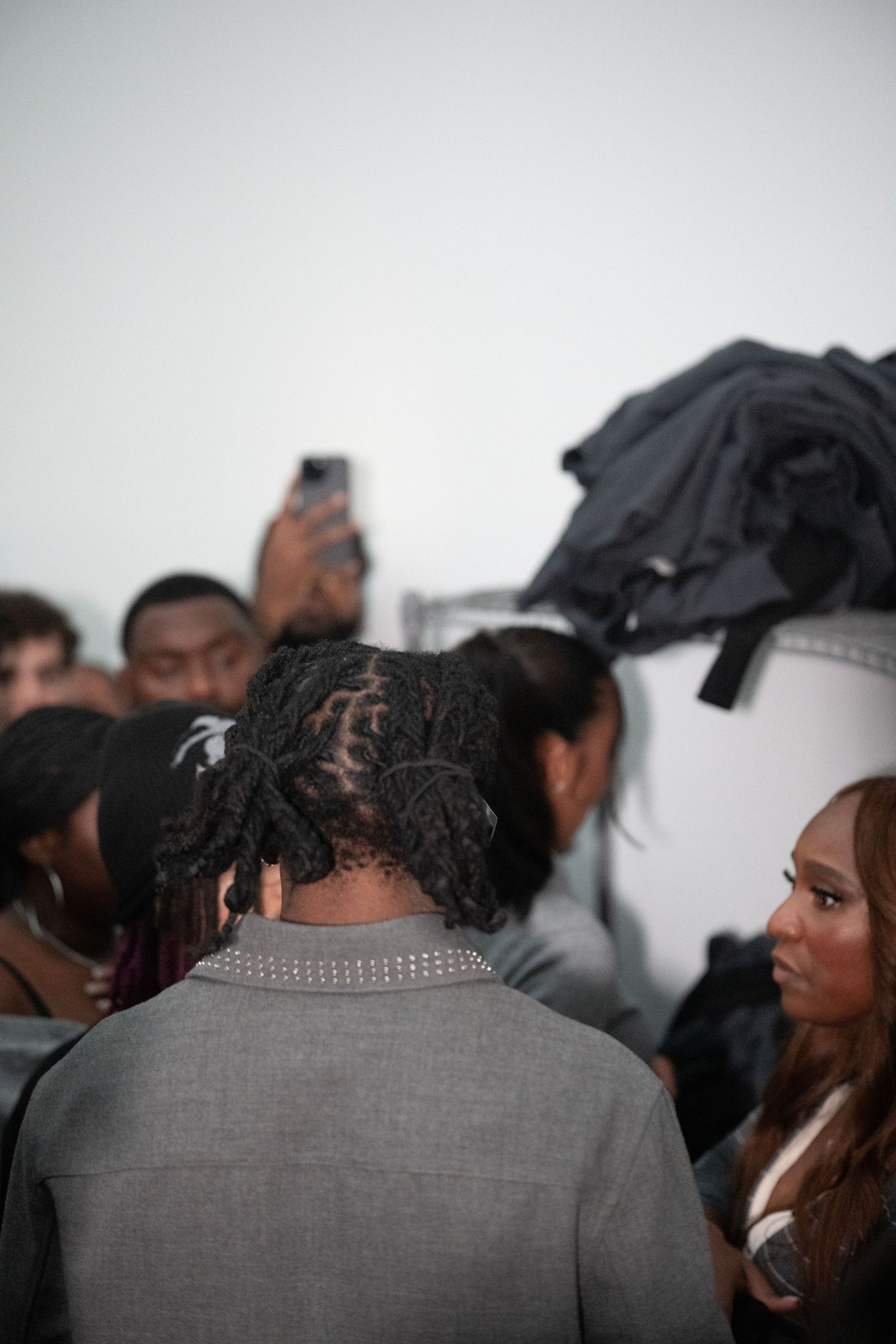 Group of people gathered in gallery space viewed from behind in dramatic lighting.
